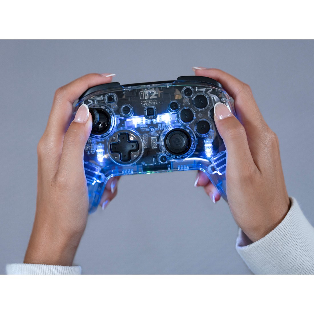 Hände halten einen transparenten Nintendo Switch Controller mit blauen Lichtern.