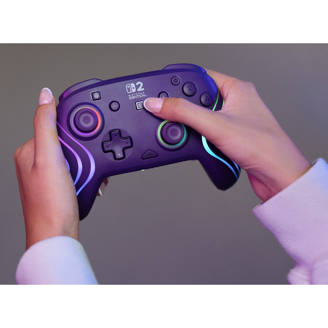 Person hält eine violette Nintendo Switch-Controller mit Lichtern.