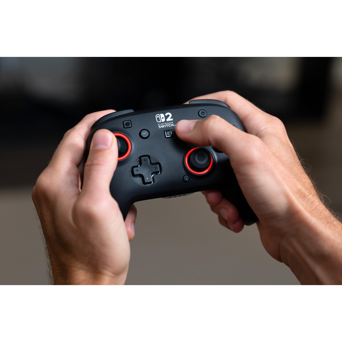 Hände halten einen schwarzen Nintendo Switch Controller mit roten Akzenten.