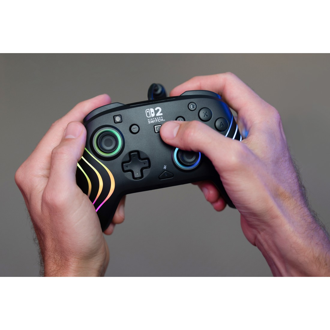 Hände halten einen schwarzen Nintendo Switch Controller mit bunten Lichtern.