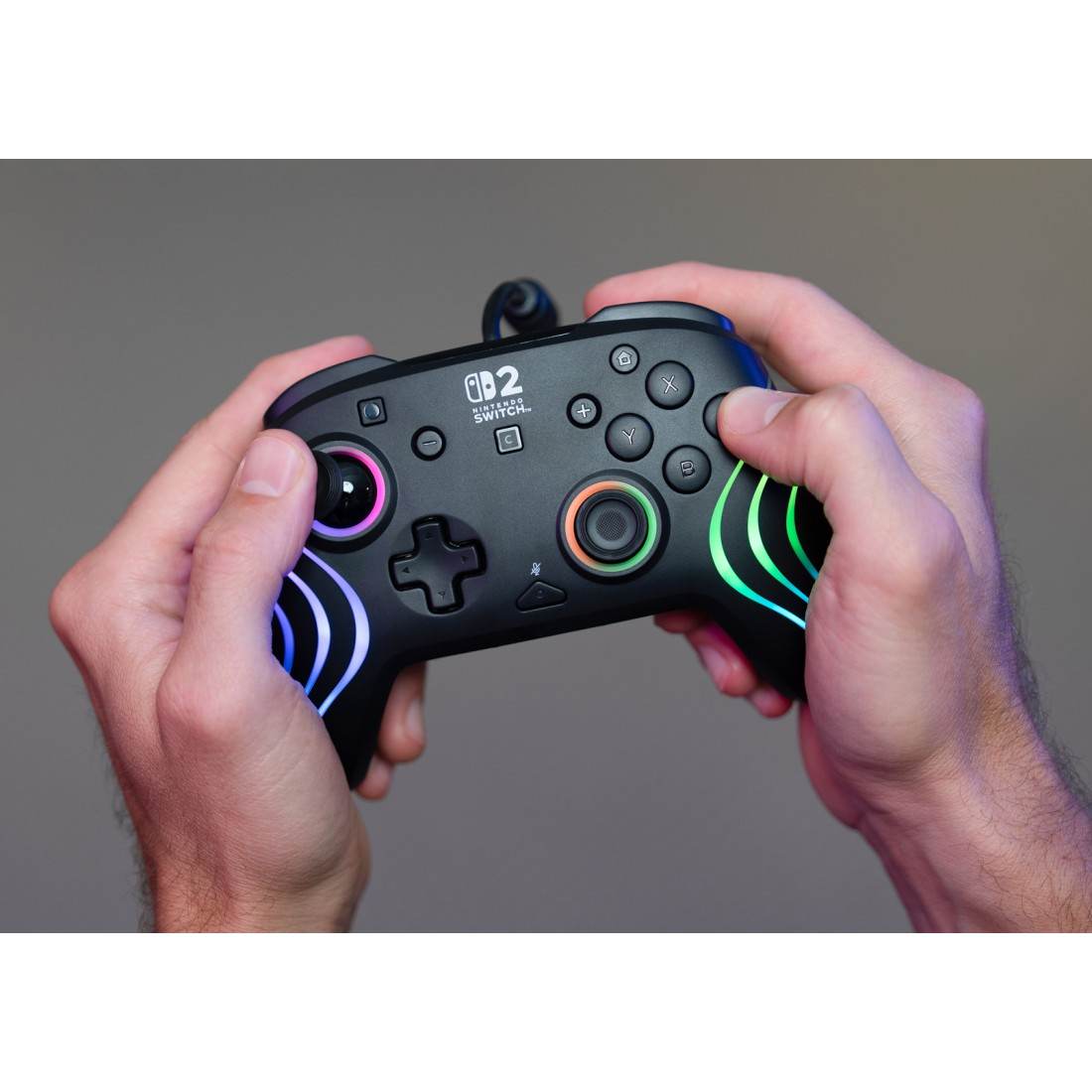 Hände halten einen schwarzen Nintendo Switch Controller mit bunten Lichtern.