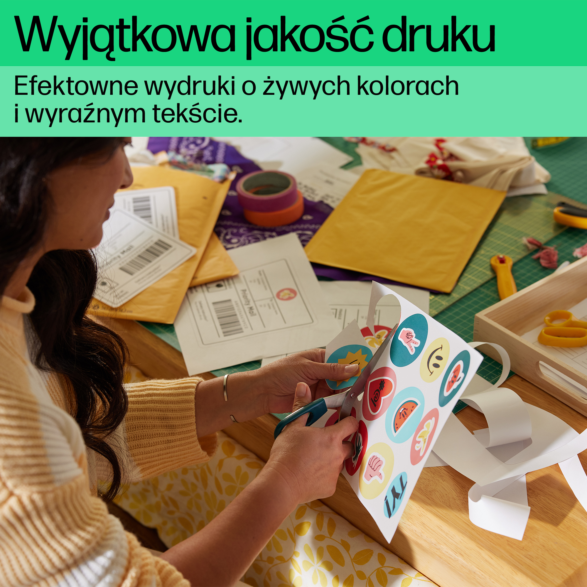 Kobieta nożyczkami wycina naklejki. Na stole leżą żółte i białe koperty.