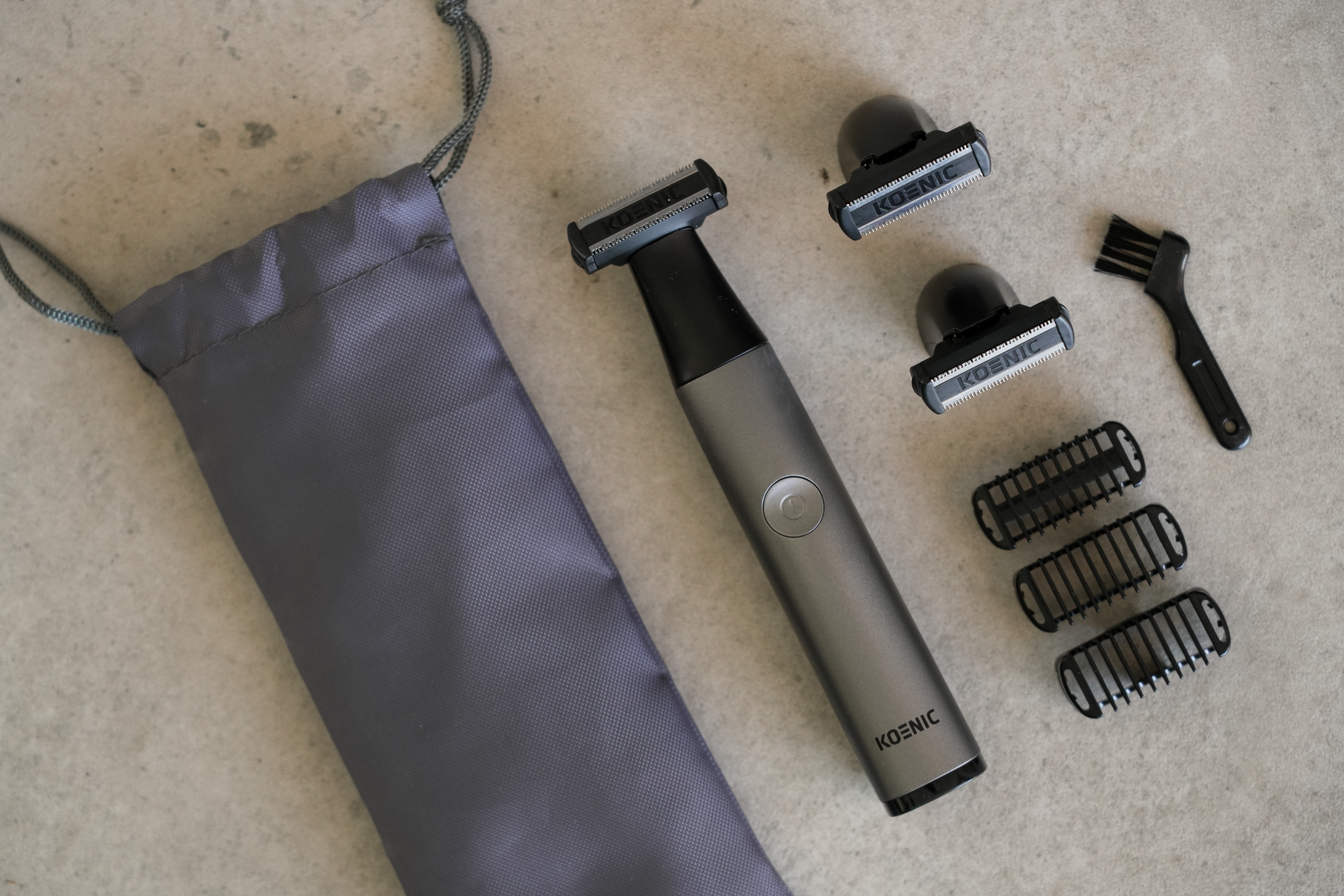 Szara maszynka do strzyżenia z akcesoriami, w tym nasadkami i szczoteczką.