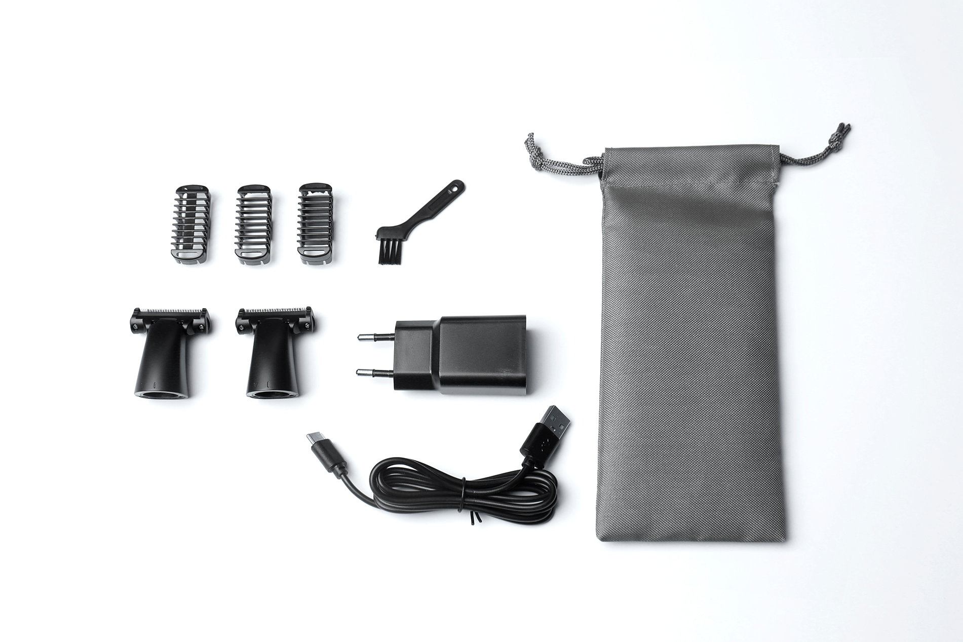 Zestaw nasadek do trymera, kabel ładujący, wtyczka, szczotka i etui na białym tle.