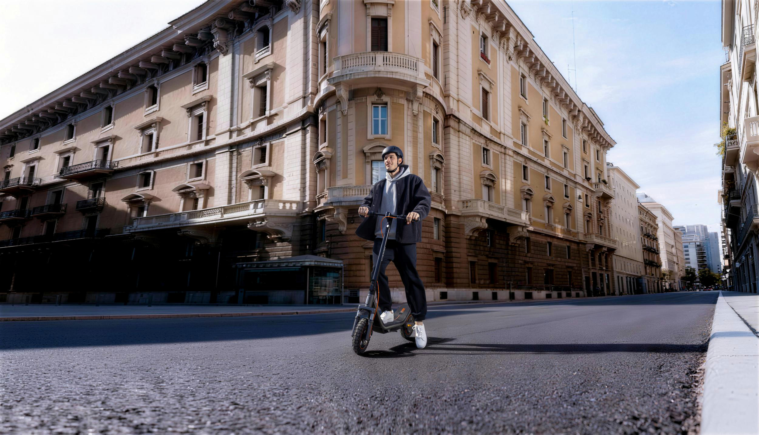Ein Mann fährt einen E-Scooter auf einer Straße vor einem historischen Gebäude.