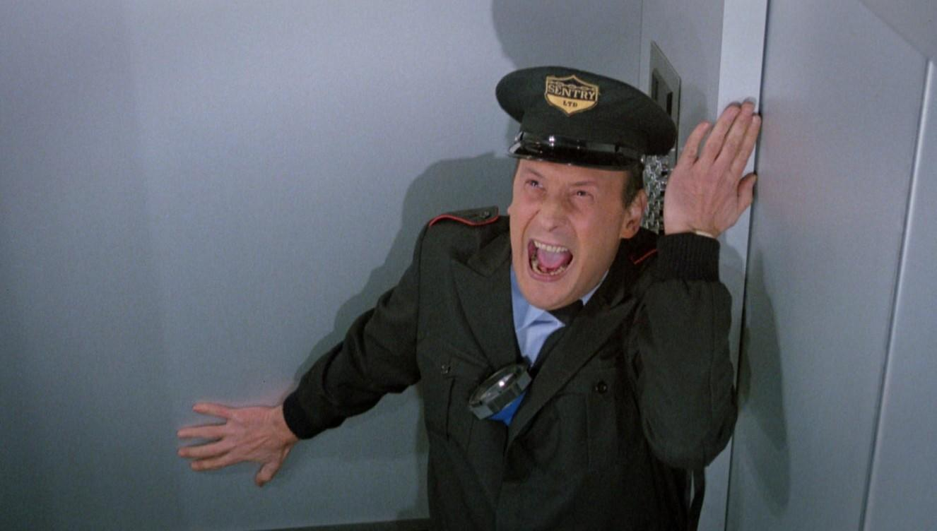 Ein Mann in Uniform schreit und lehnt sich an eine Wand.