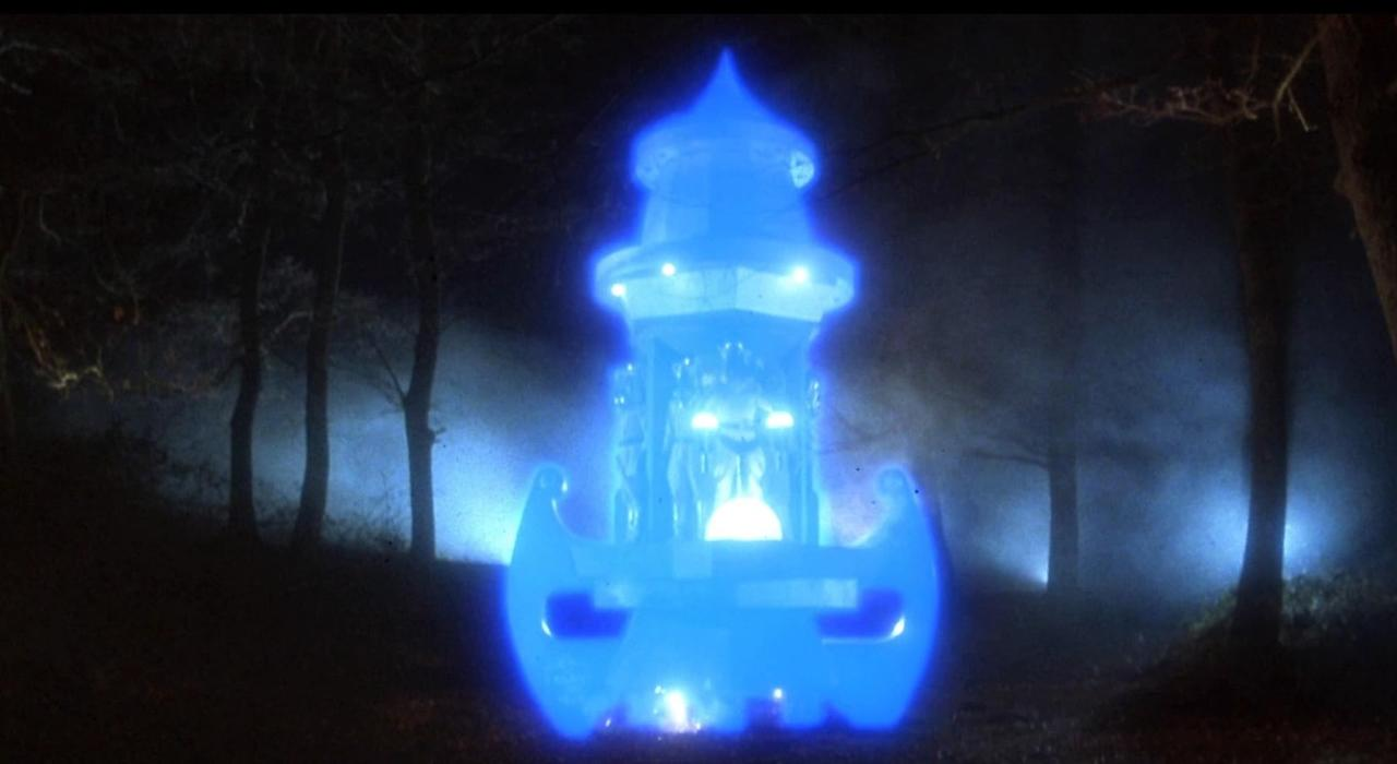 Ein leuchtendes blaues Objekt steht im Nebel auf einem dunklen Waldboden.