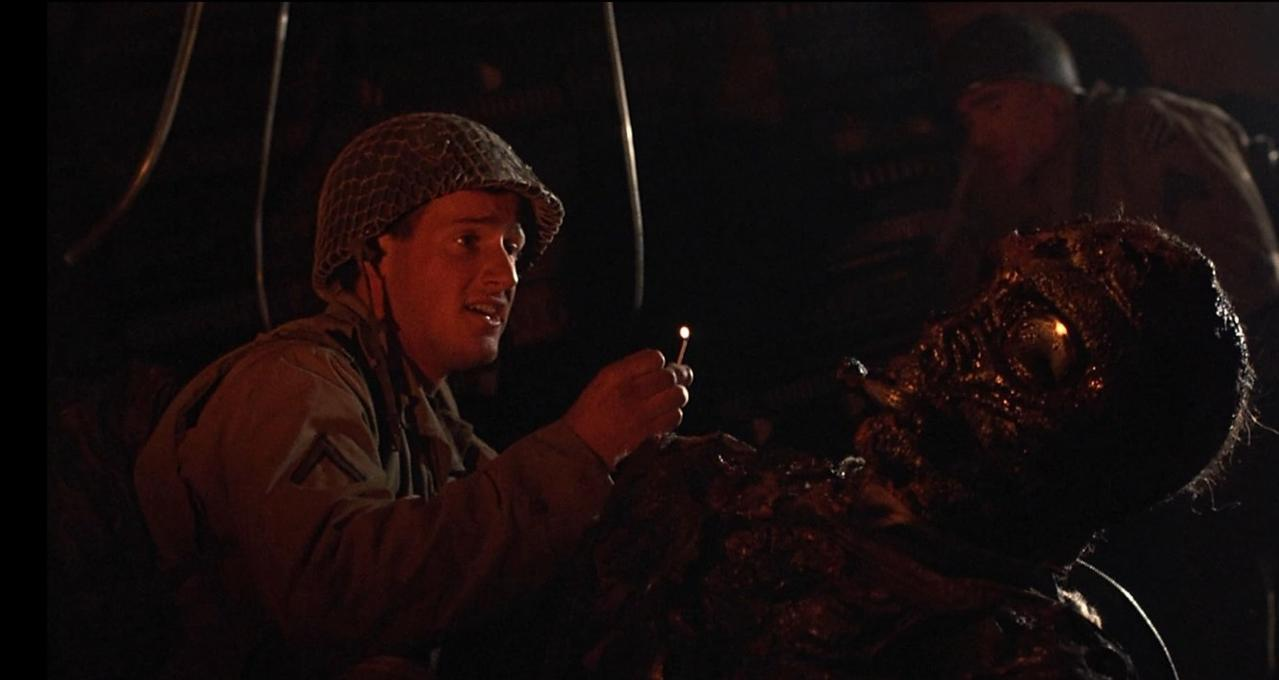 Soldat mit Helm hält brennende Zündholzschachtel vor groteskes Gesicht.