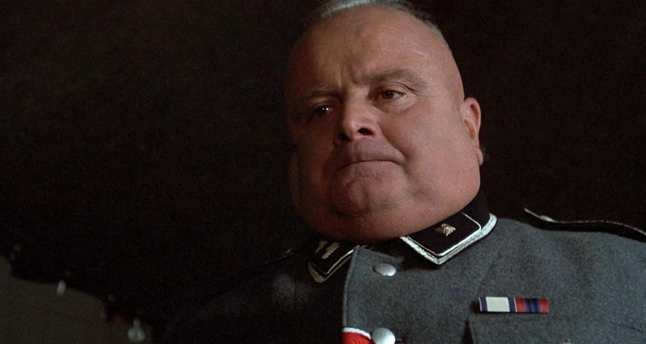 Ein korpulenter Mann in SS-Uniform mit grauem Mantel und Orden.