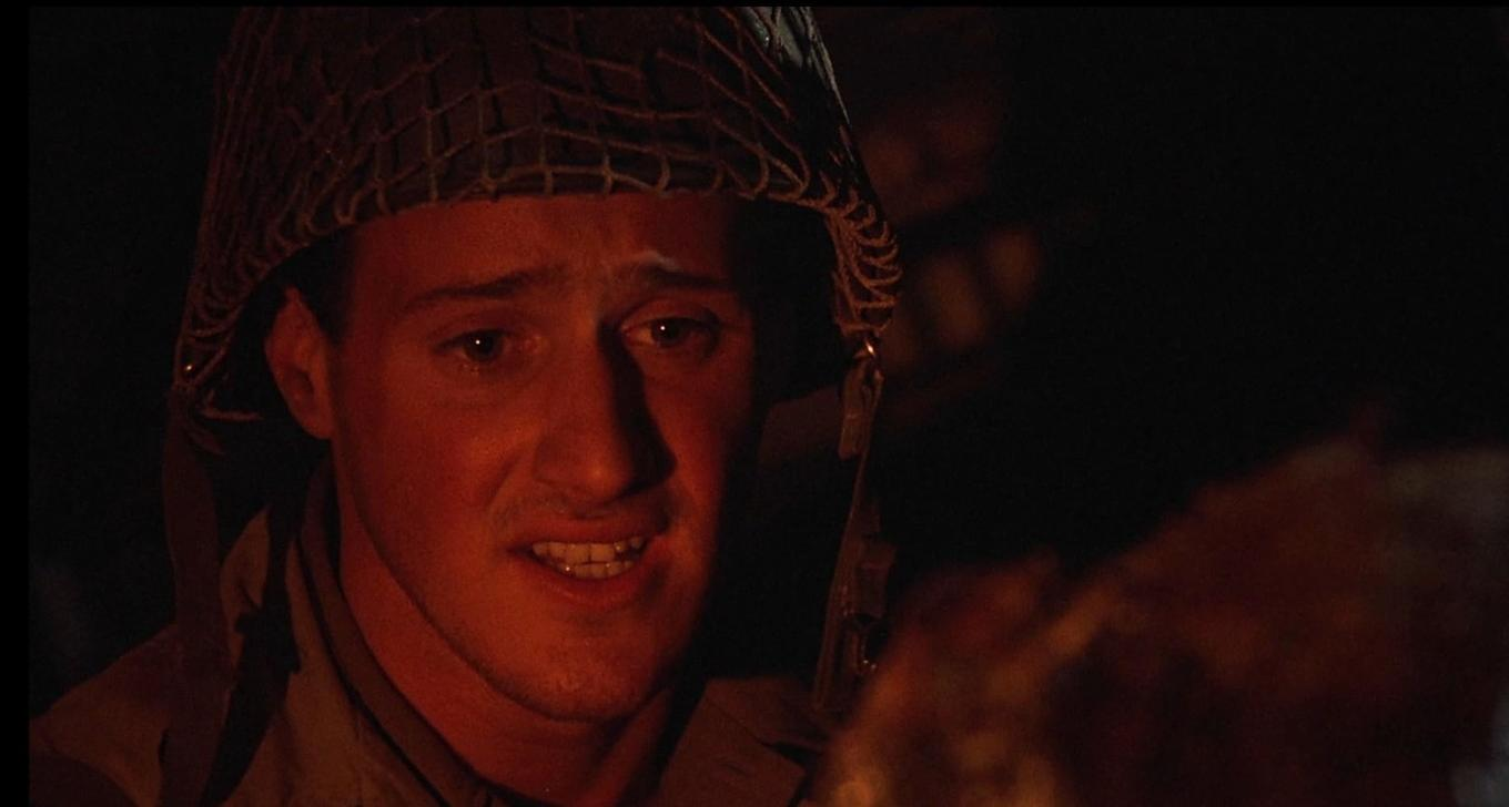 Ein Soldat mit Helm spricht in der Dunkelheit, sein Gesicht ist gerötet.