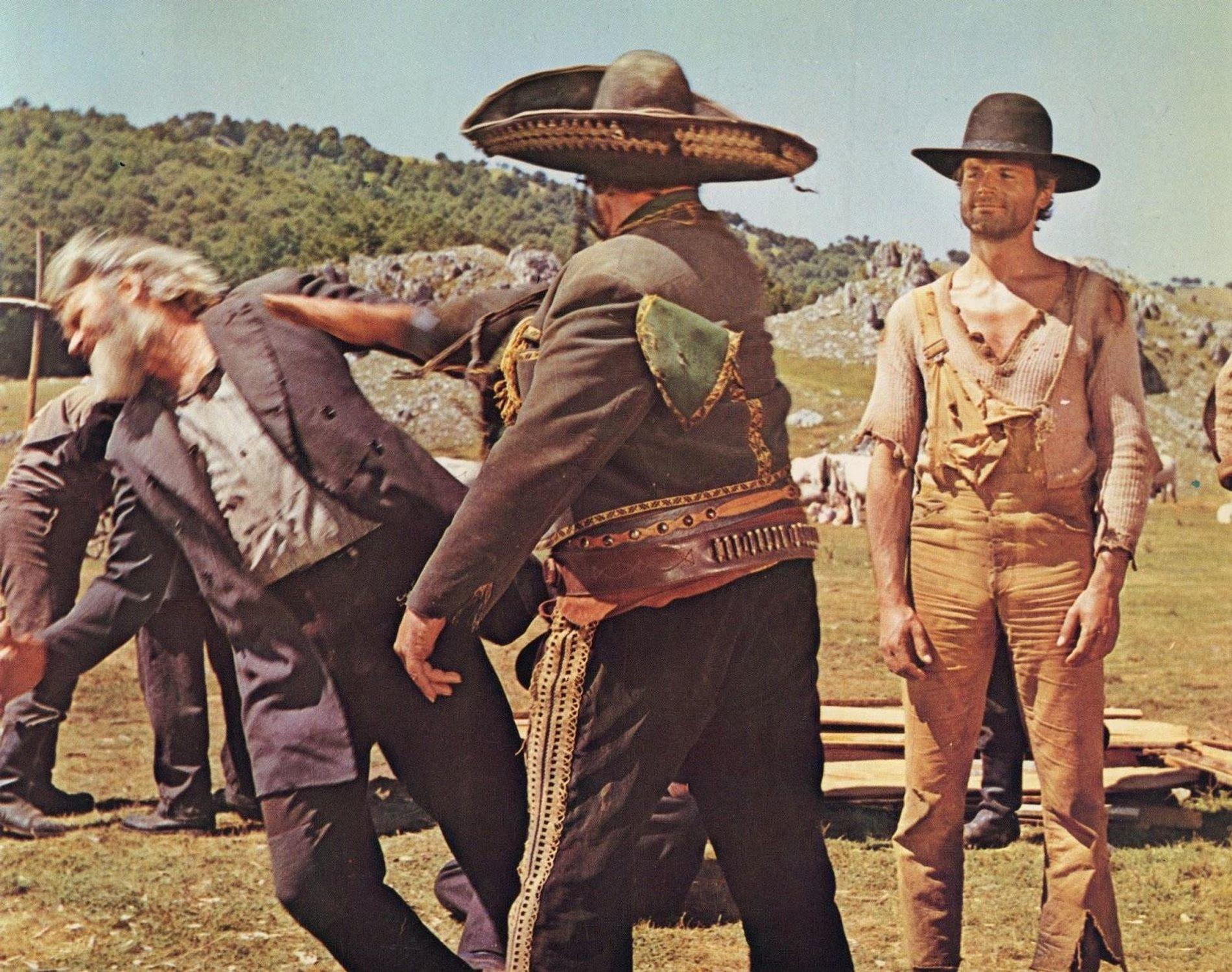 Ein Mann im Mariachi-Outfit greift einen älteren Mann an. Ein weiterer Mann steht daneben.