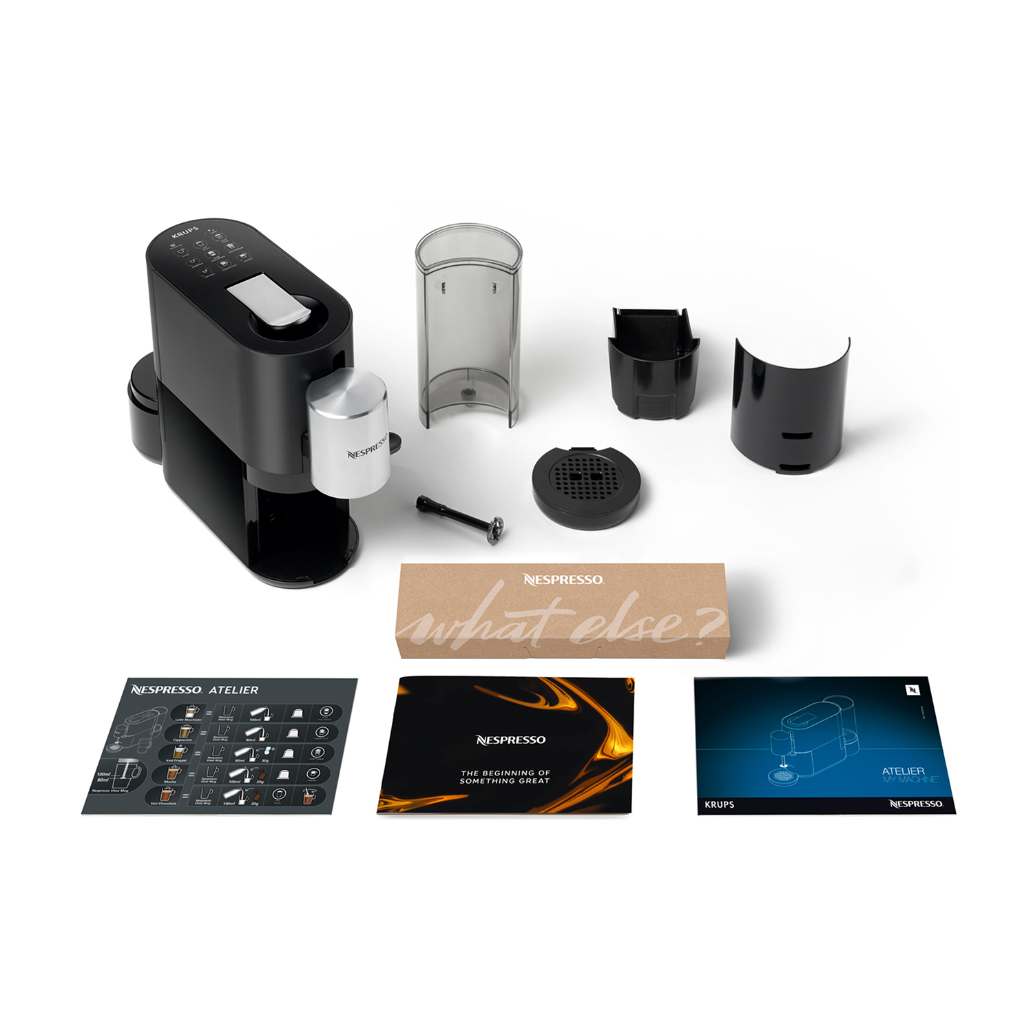 Macchina Nespresso nera con accessori e manuali su sfondo bianco.