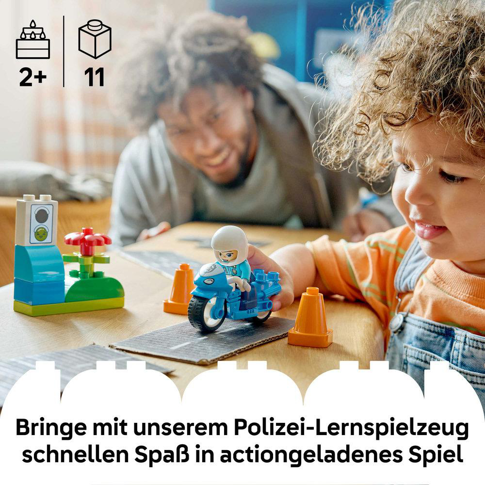 Ein Kind spielt mit einem Polizei-Motorrad-Spielzeug, ein Mann schaut zu.