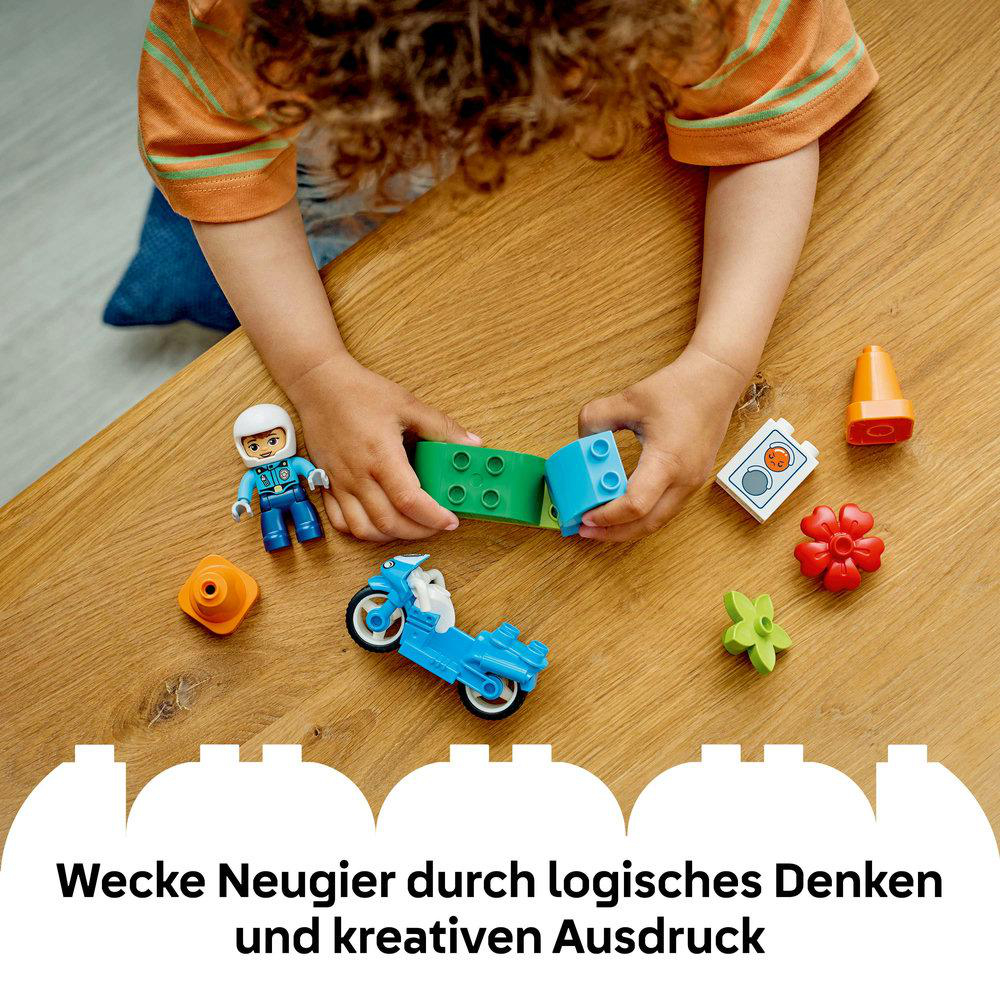 Ein Kind spielt mit bunten Bausteinen, einer Figur und einem Motorrad.
