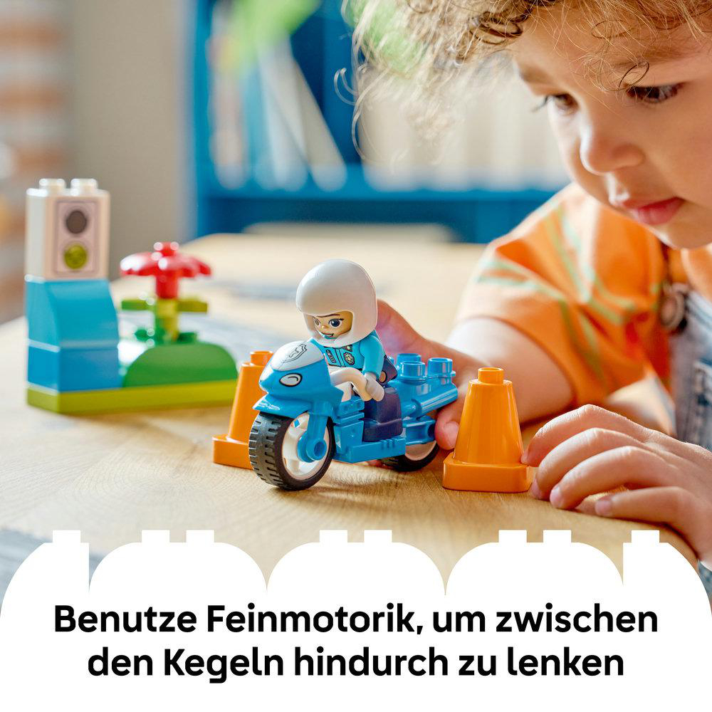 Kind lenkt blauen Motorrad-Spielzeug durch orange Hütchen auf Holztisch.
