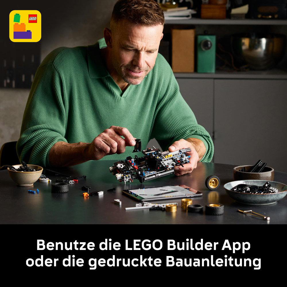 Mann baut Lego-Auto, Lego-Logo oben links. Bauanleitung auf dem Tisch.