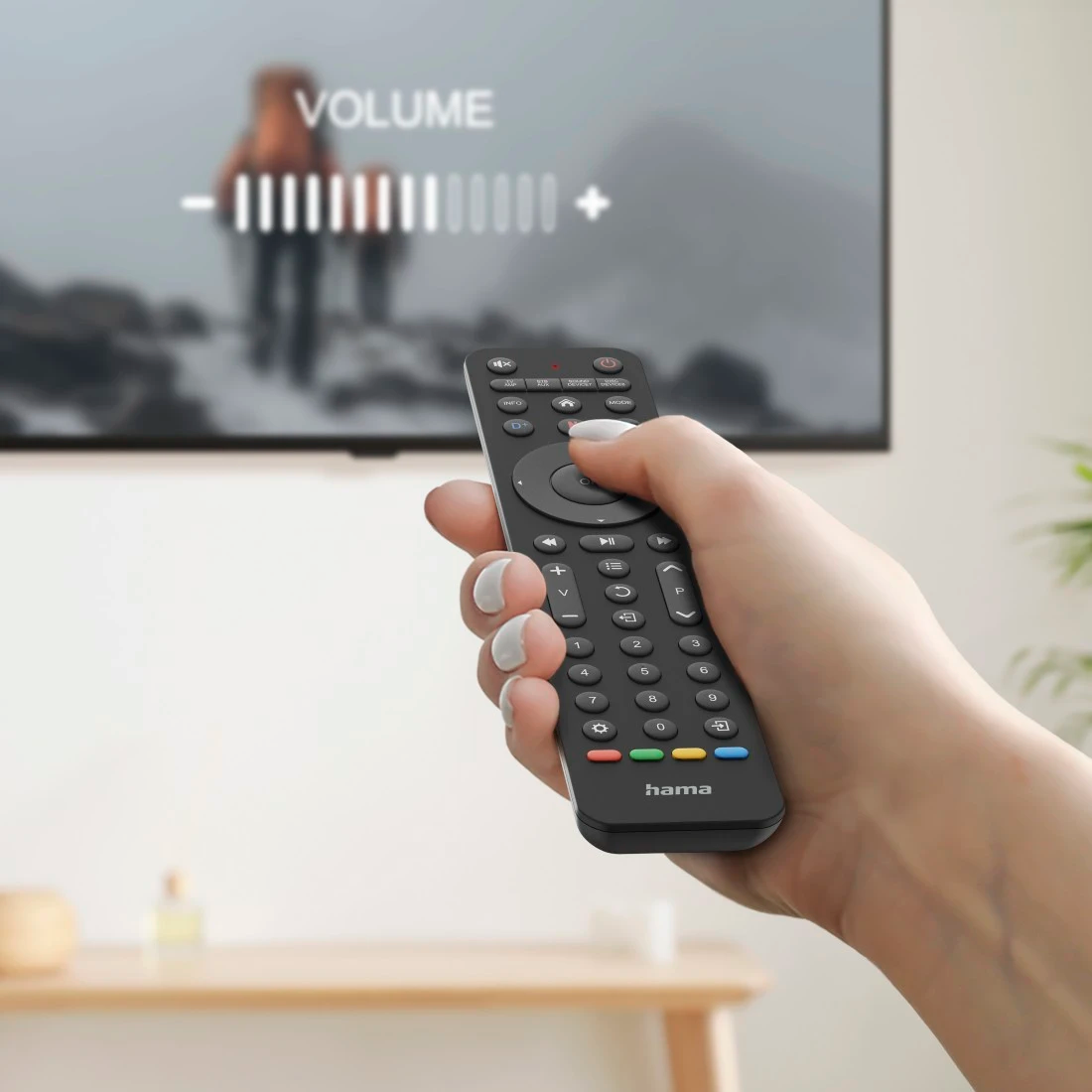 Egy kéz távirányítót tart a TV-képernyő előtt, amely a hangerőszabályzót mutatja.