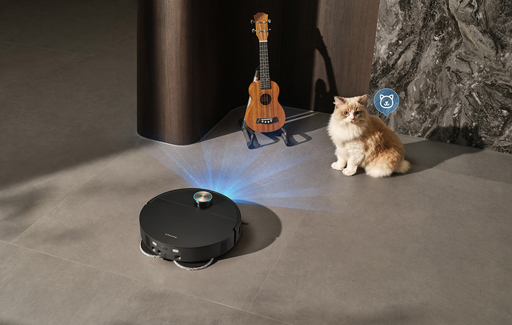 Robot sprzątający czyści podłogę obok kota i ukulele.