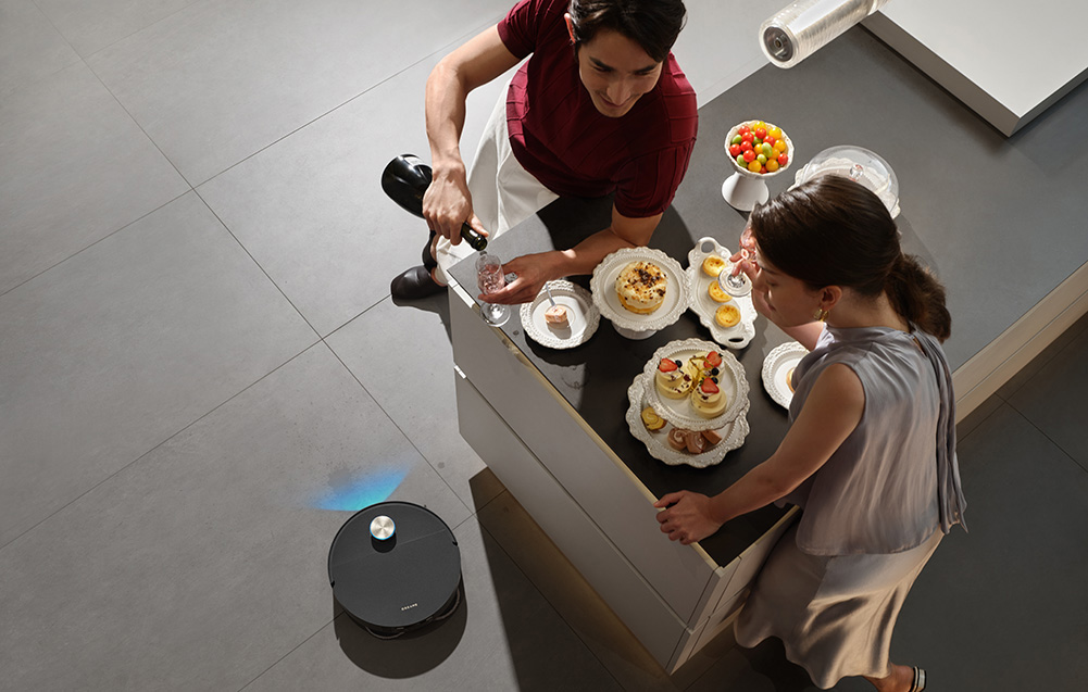 Mężczyzna nalewa drinka, podczas gdy kobieta stoi przy stole z deserami.