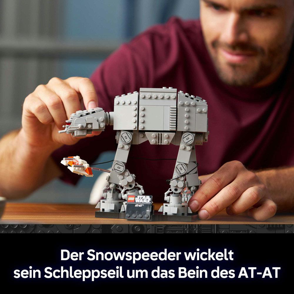 Ein Mann baut einen grauen AT-AT Walker mit einem kleinen Snowspeeder, der daran befestigt ist.