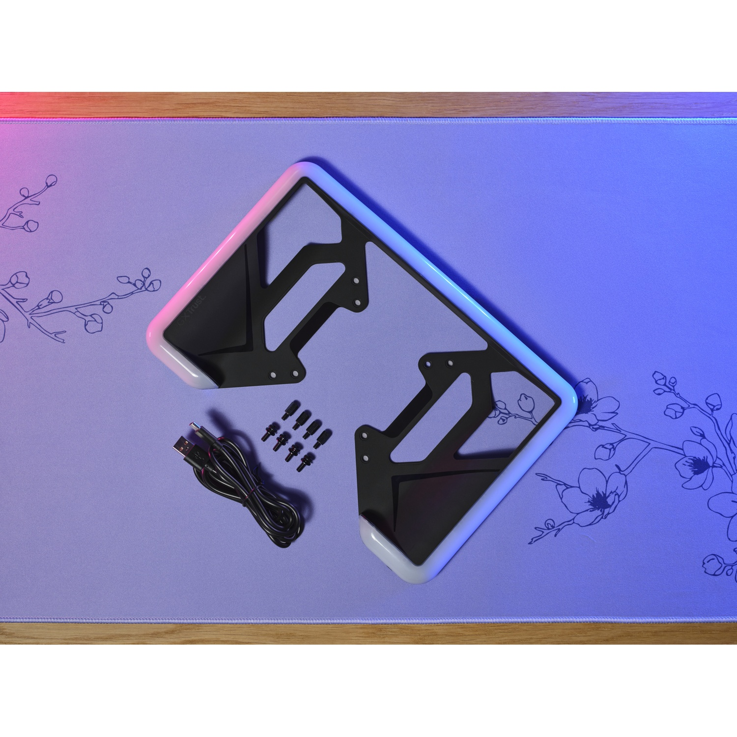 A black frame with RGB lighting lies on a purple mat with floral patterns.