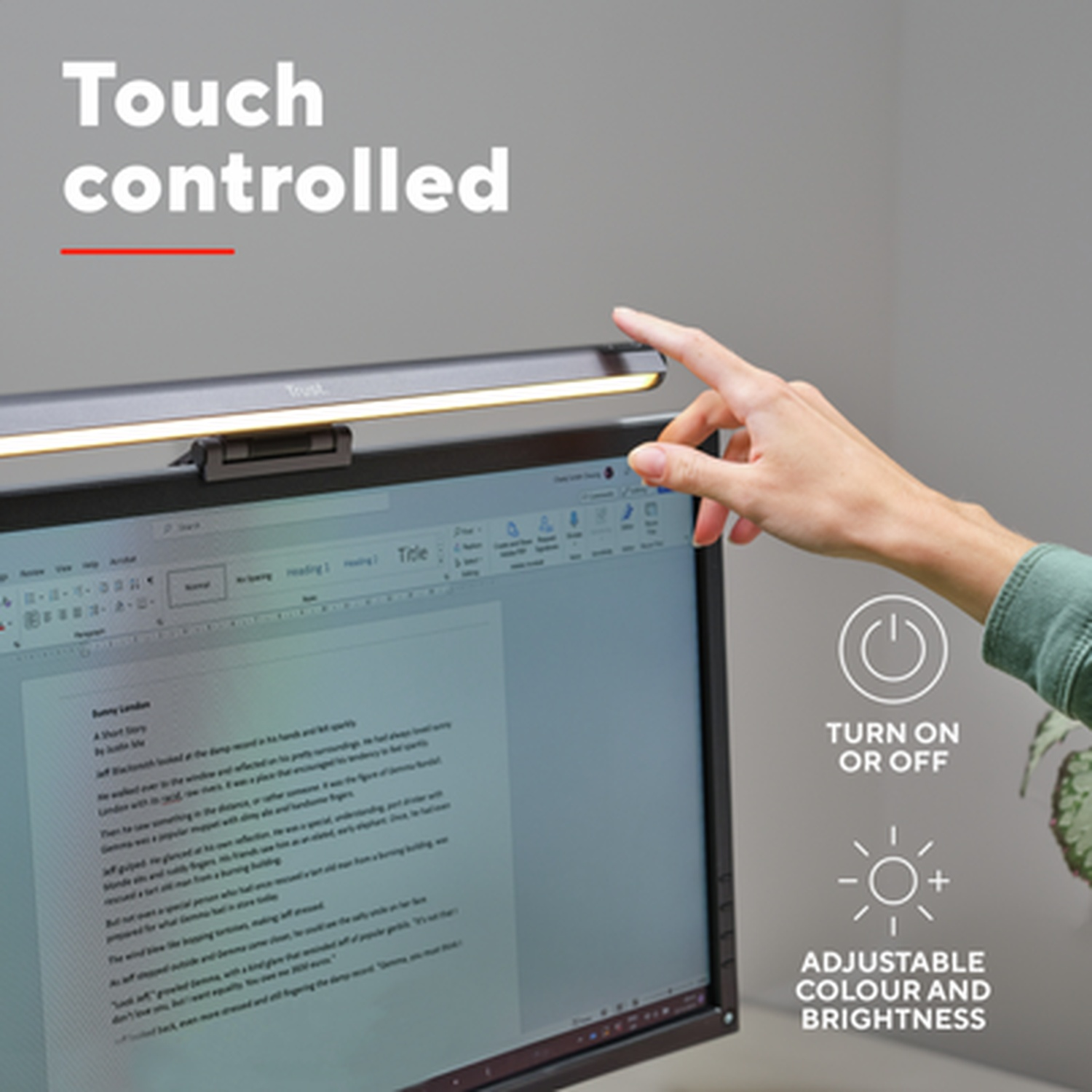 A hand touches a screen-mounted light bar above a monitor displaying text.