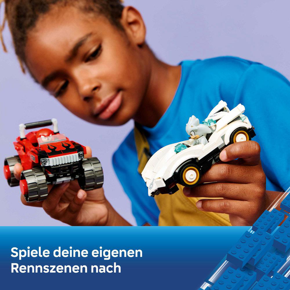 Ein Junge hält ein rotes und ein weißes Spielzeugauto. Blaue Legosteine im Hintergrund.
