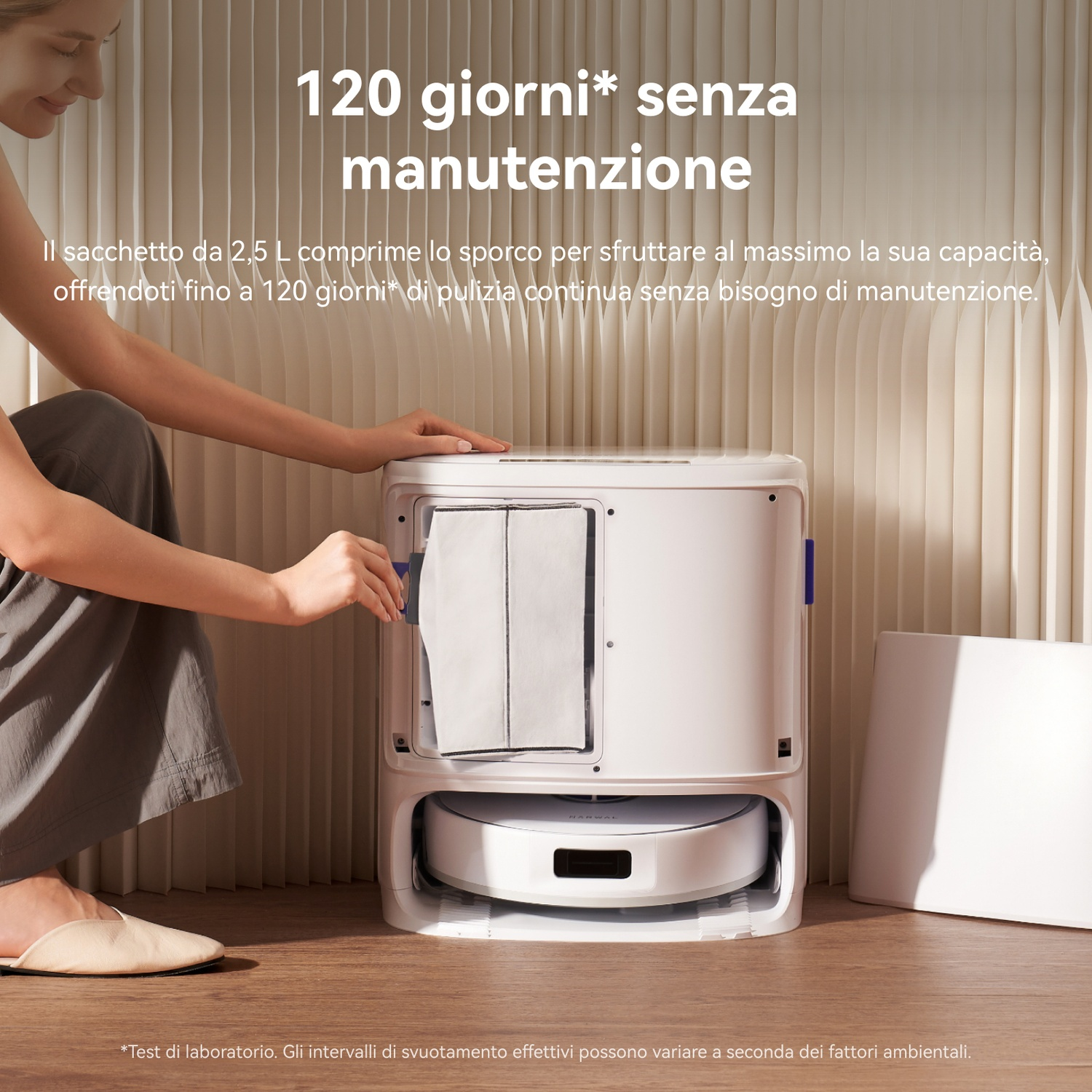 Una donna cambia il sacchetto per la polvere di una stazione di pulizia bianca per robot.