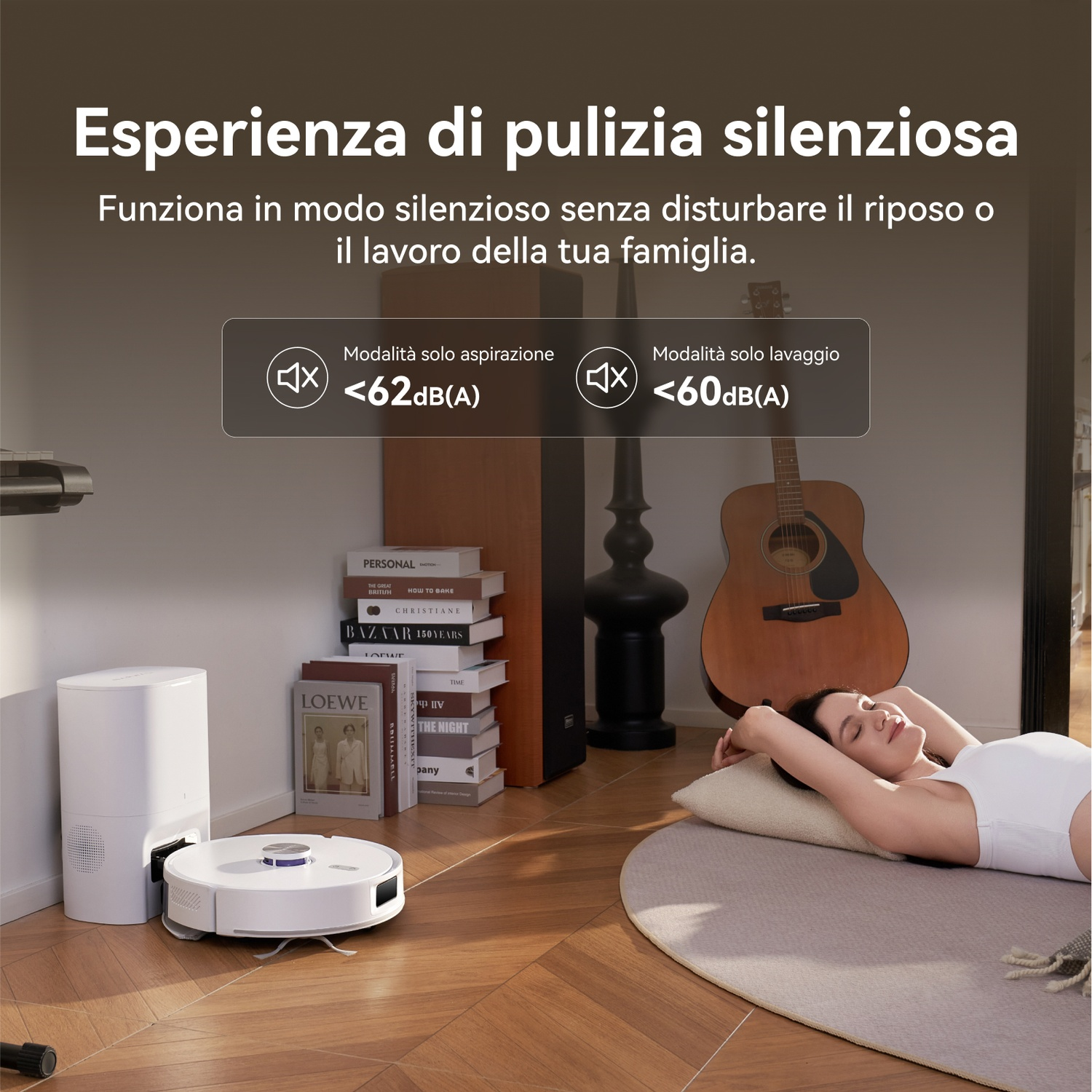 Un robot aspirapolvere accanto alla sua base di ricarica. Una donna dorme su un tappeto.