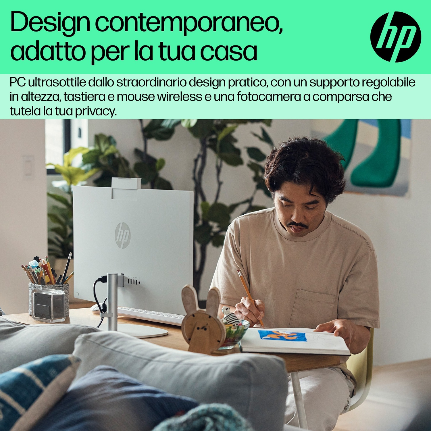 Uomo siede alla scrivania, disegna su un quaderno, PC HP sullo sfondo.