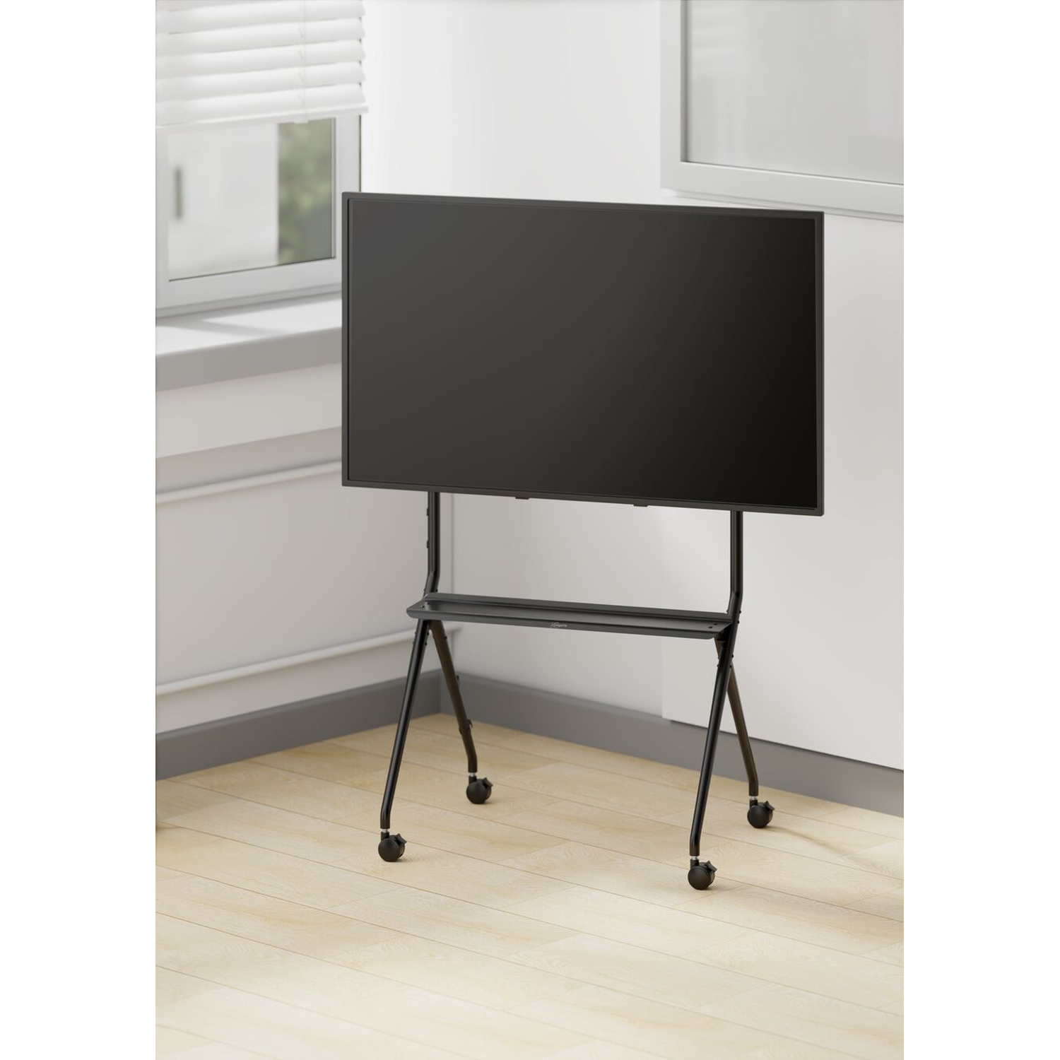 Een zwarte monitor op een rolstandaard in een lichte kamer met houten vloer.