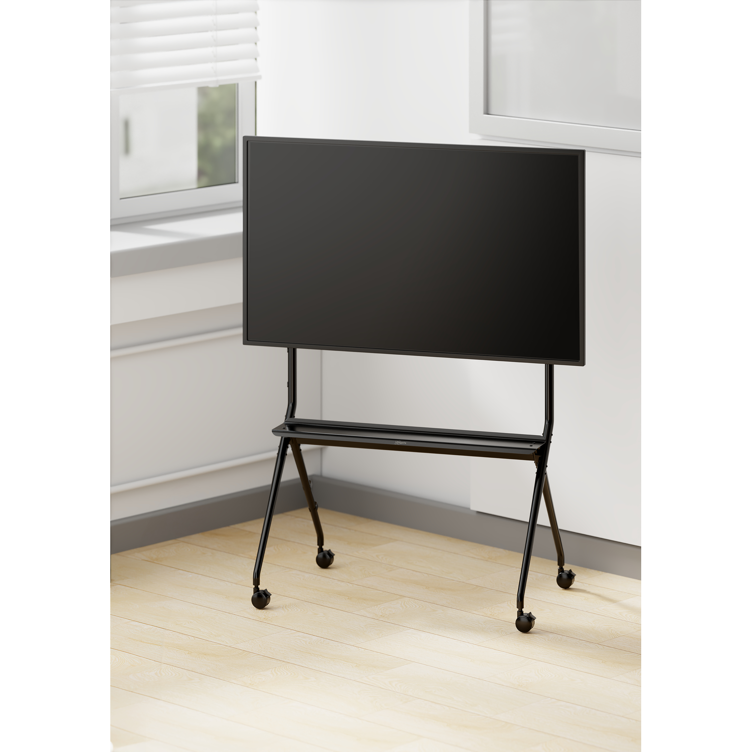 Een zwarte monitor op een rolstandaard staat in een lichte kamer met houten vloer.