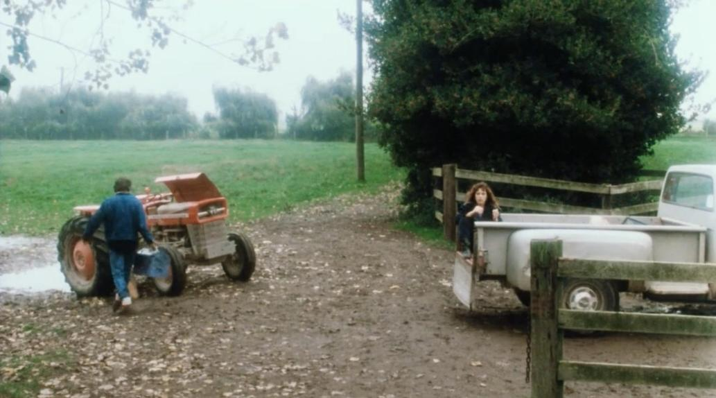 Ein Mann geht zu einem Traktor. Ein Mädchen sitzt auf einem Pick-up-Truck.
