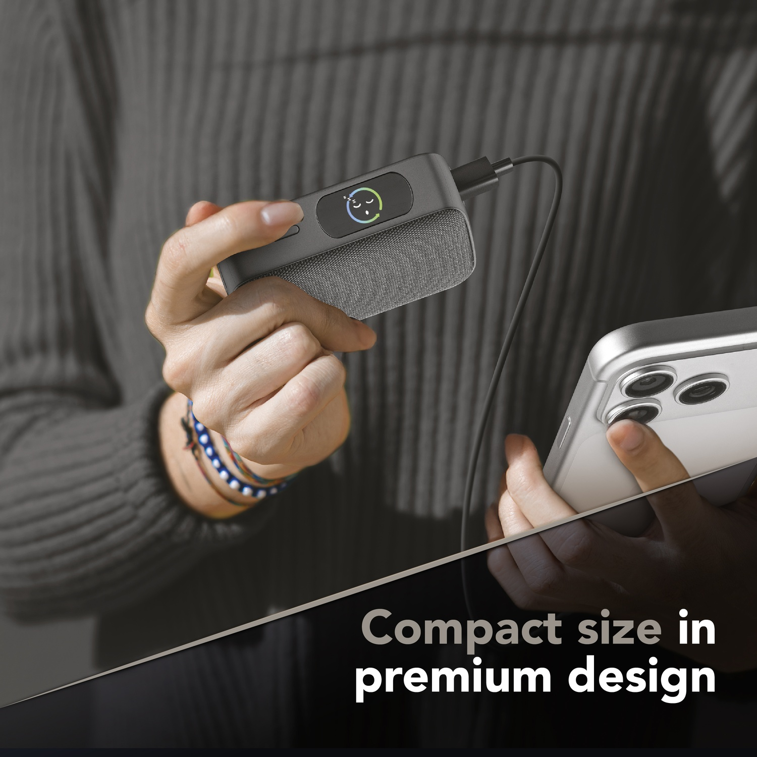 Power bank grigio con tessuto collegato a un telefono. Faccina sorridente addormentata sul power bank.