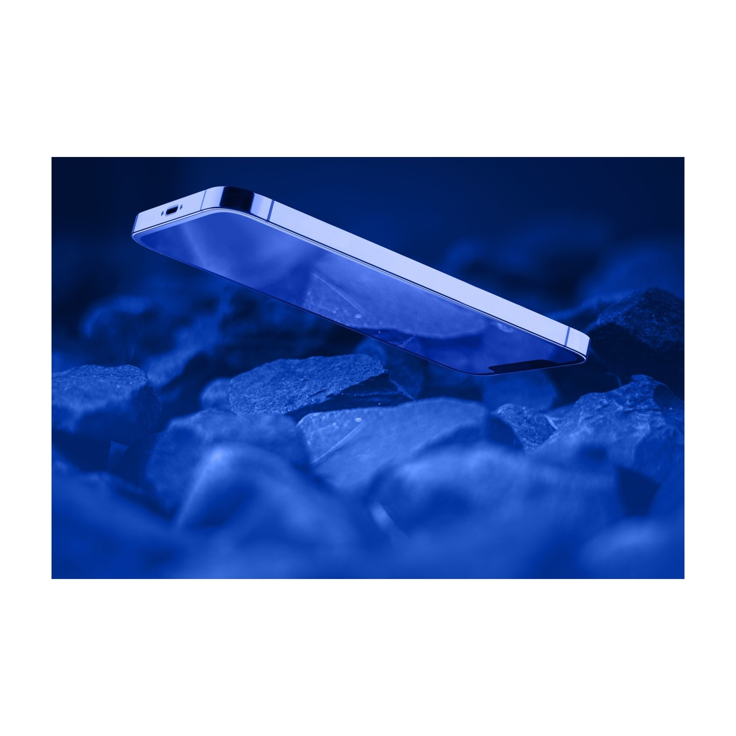 Uno smartphone moderno poggia su pietre scure, il tutto immerso nella luce blu.
