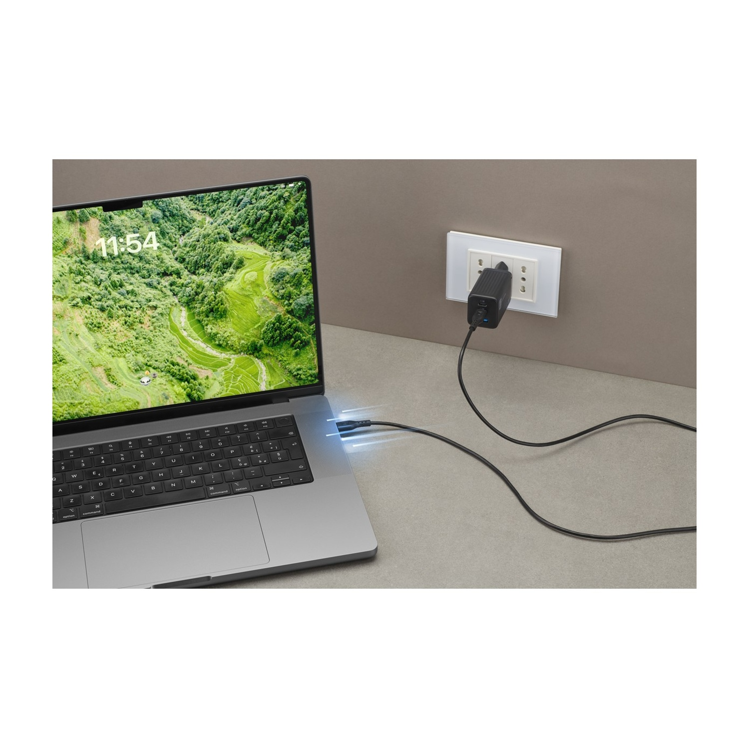 Un laptop si sta caricando tramite un cavo USB nero collegato a un adattatore di corrente.