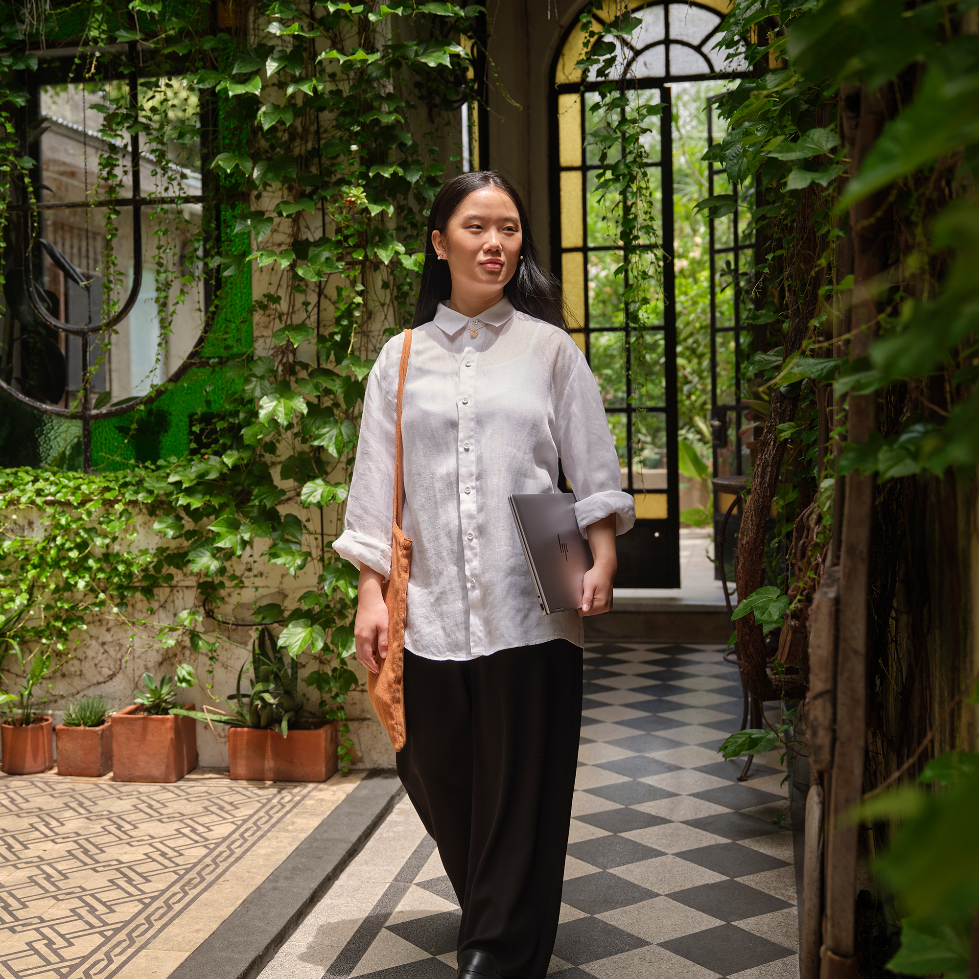 Kobieta z długimi czarnymi włosami idzie po wzorzystej podłodze.