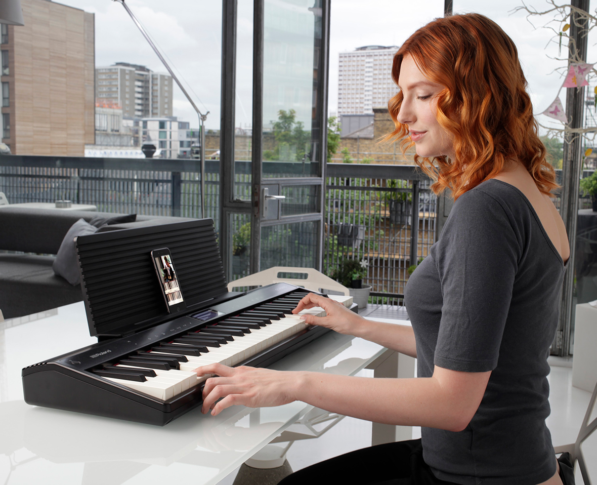 Une femme aux cheveux roux joue du clavier sur un balcon.