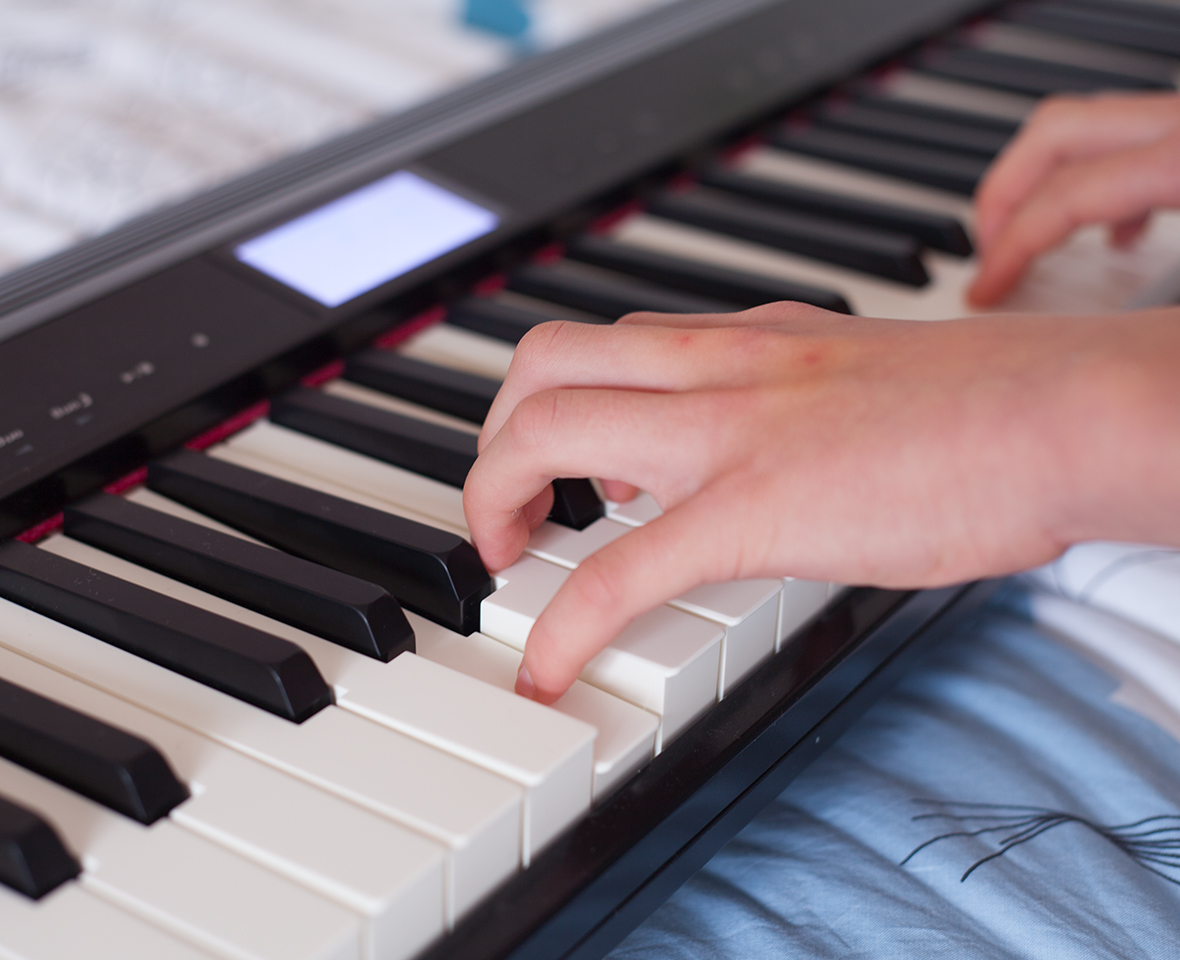 Mains jouant sur un clavier de piano avec des touches blanches et noires.