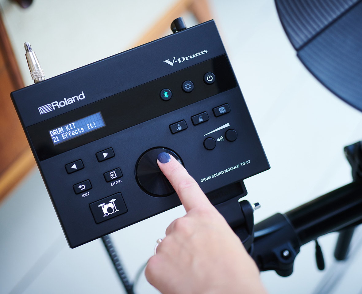 Un doigt appuie sur le bouton rond du module Roland V-Drums TD-07.