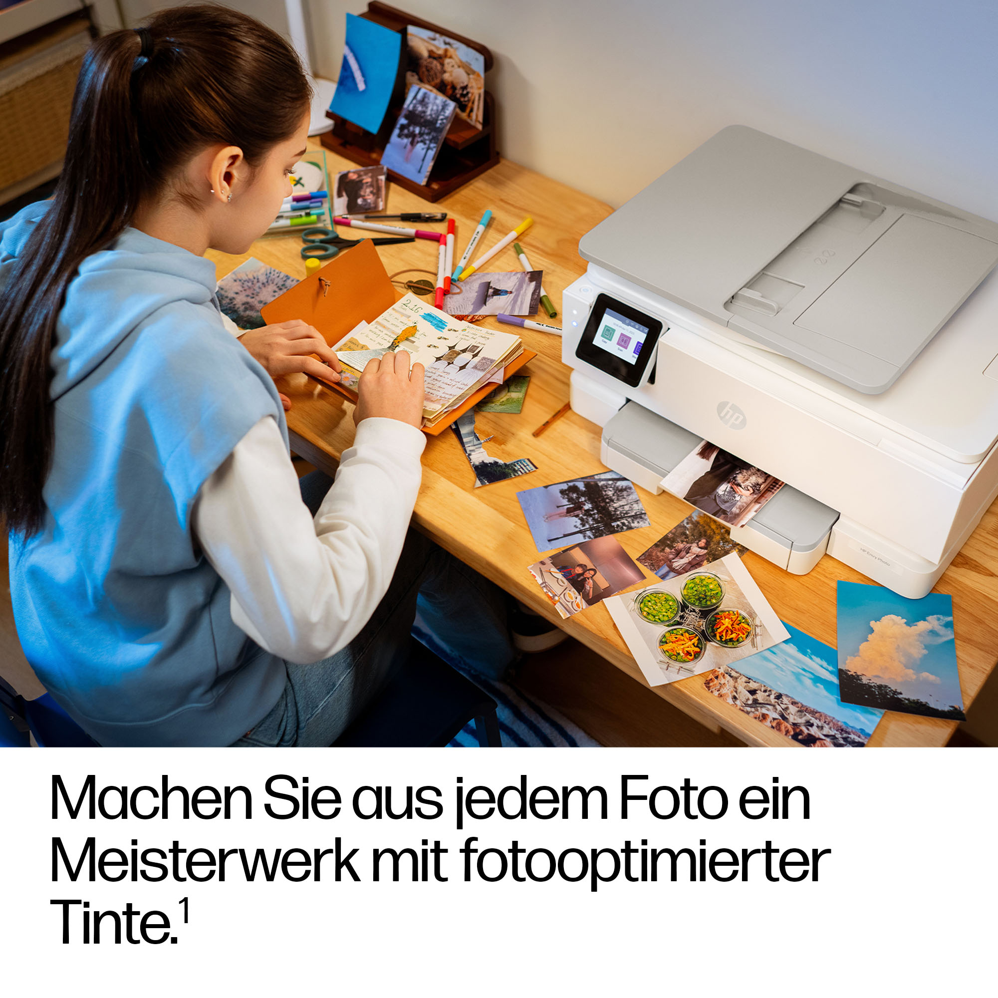 Ragazza crea album fotografico con stampante sul tavolo.
