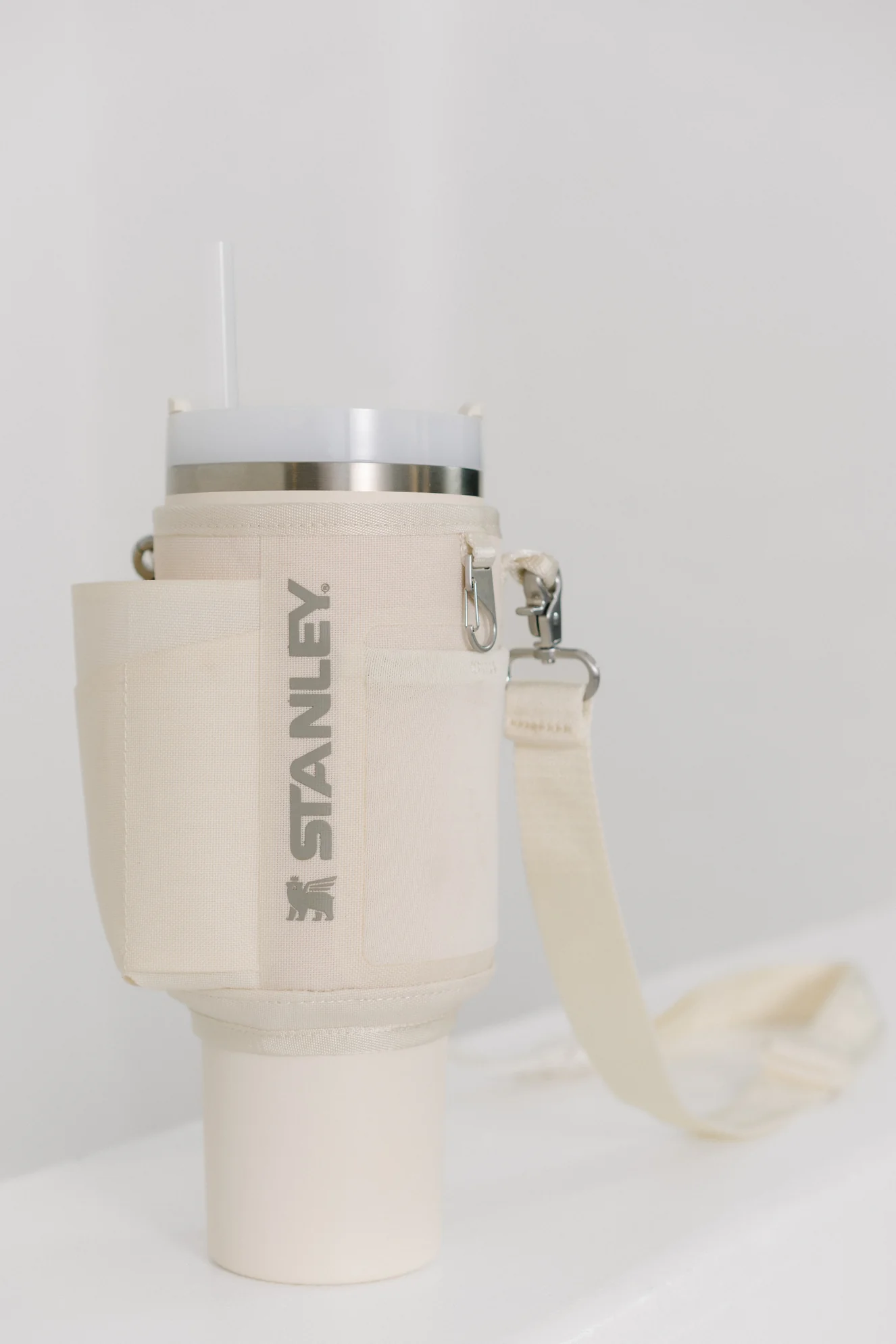 Pipetli beyaz Stanley kupa ve askılı krem rengi kumaş tutucu.