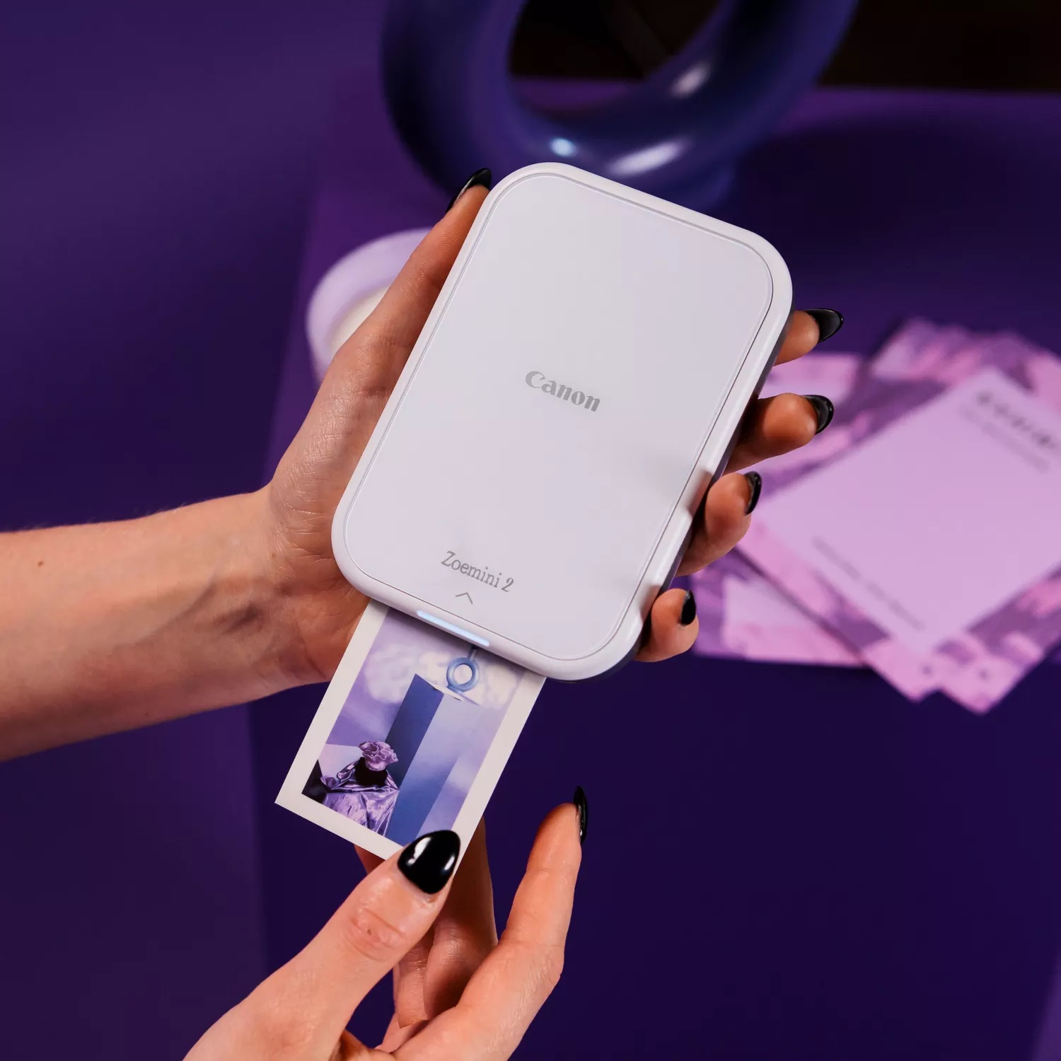 Biały Canon Zoemini 2 drukuje małe zdjęcie z fioletowymi obiektami.