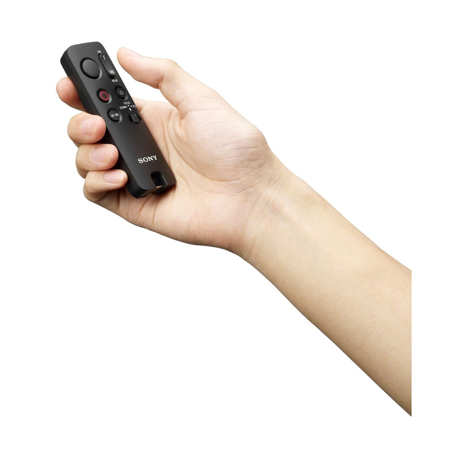 Una mano tiene un telecomando Sony nero con pulsanti per messa a fuoco e zoom.