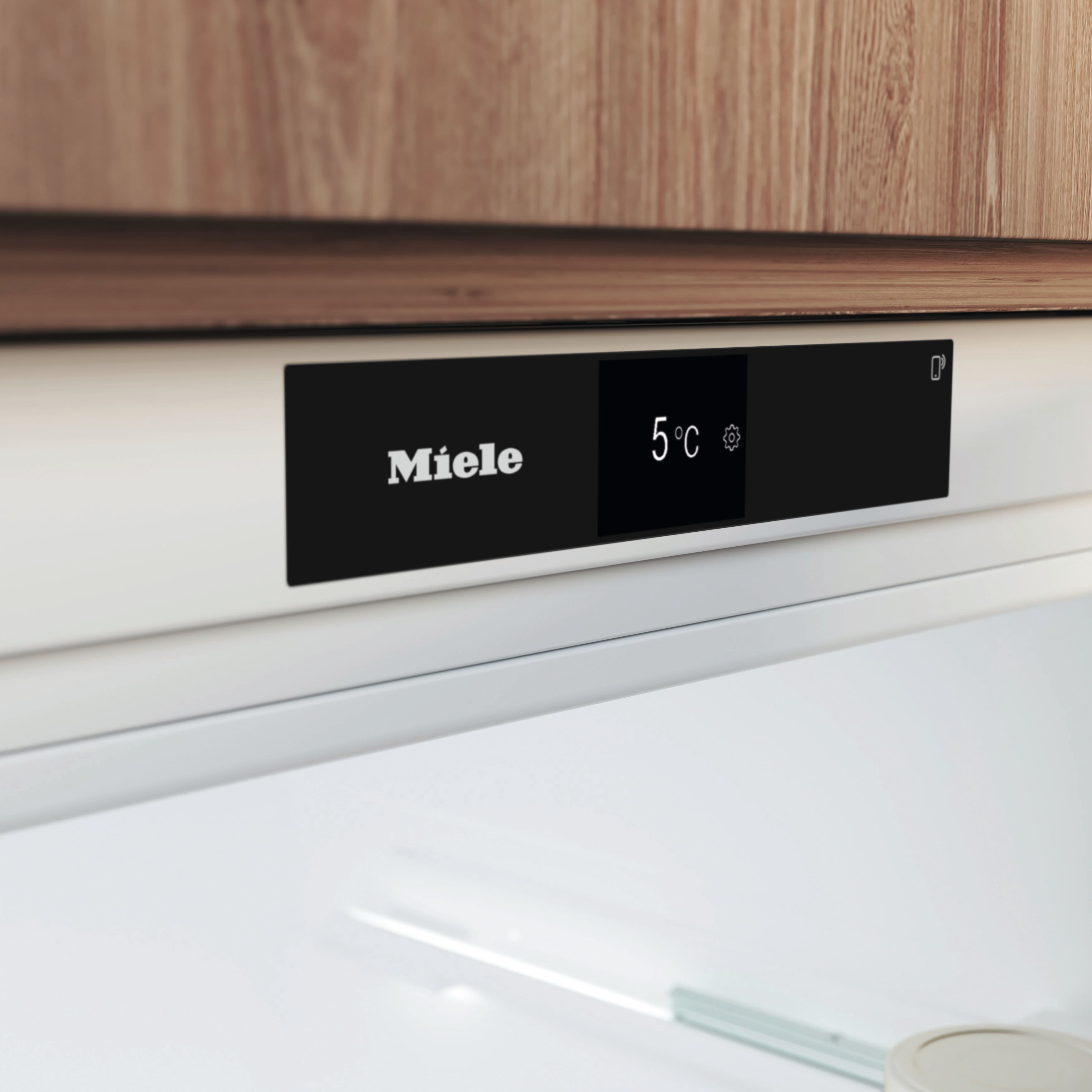 Miele-Logo und 5°C Anzeige auf einem weißen Bedienfeld über weißem Innenraum.