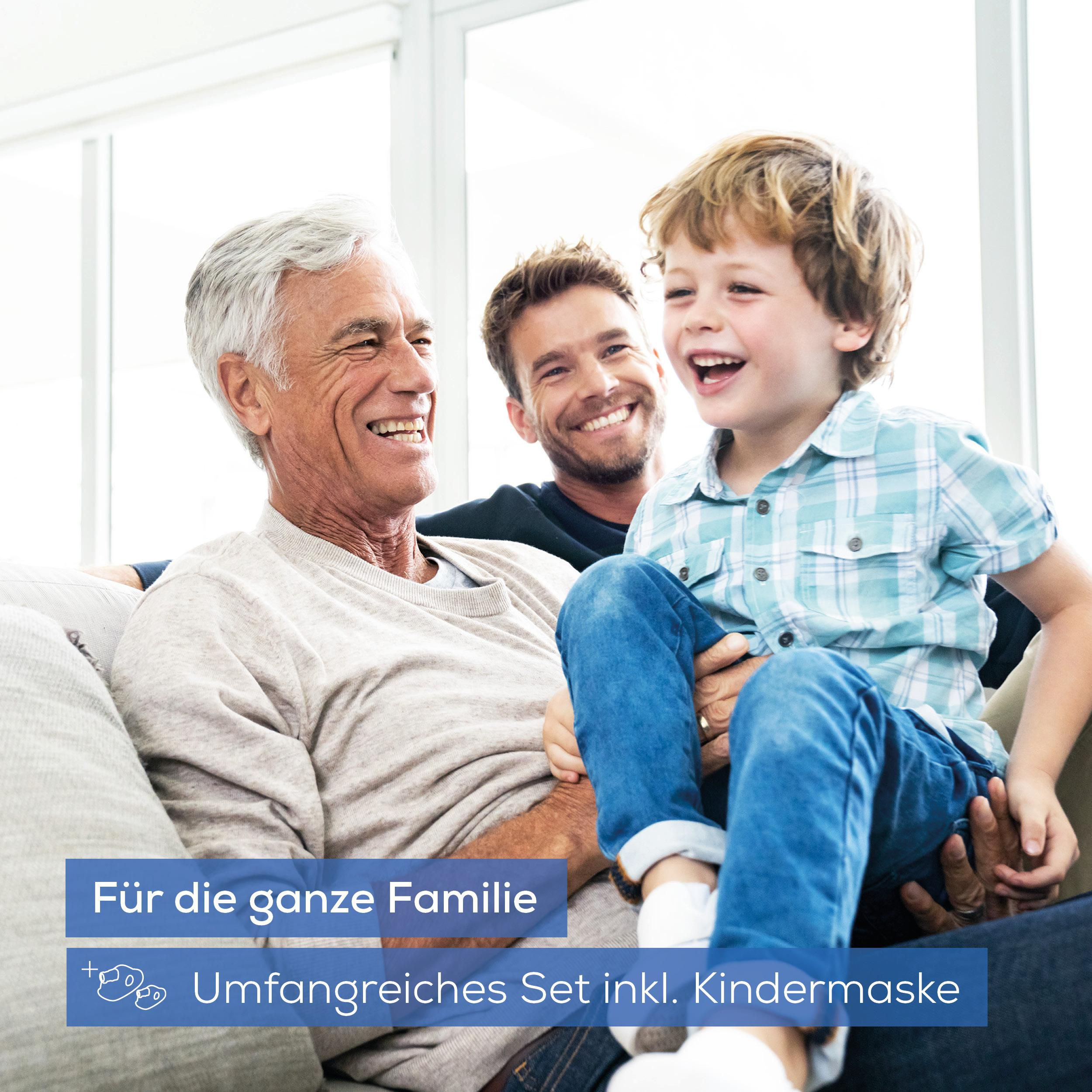 Drei lachende Männer unterschiedlichen Alters sitzen auf einem Sofa.
