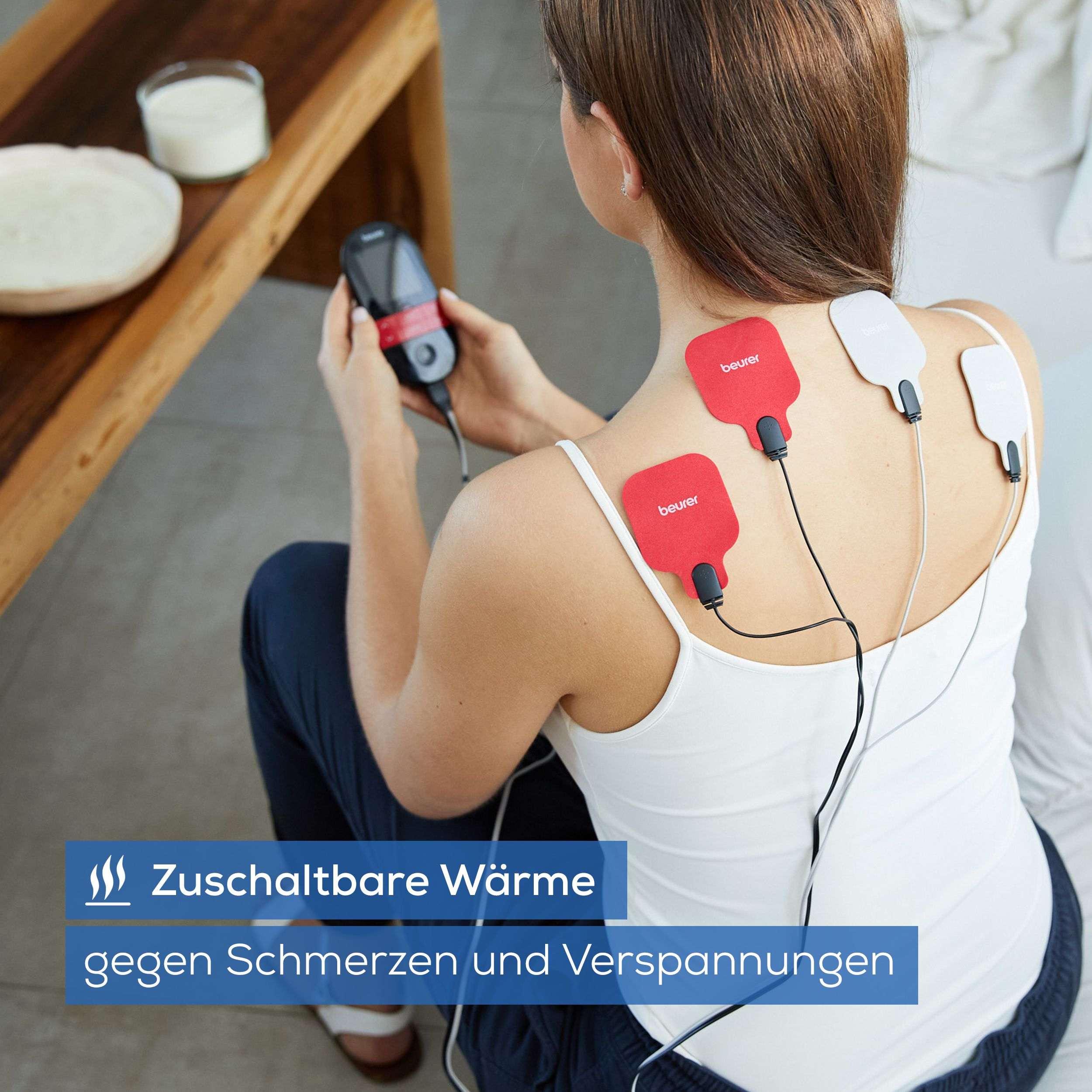 Frau mit Elektroden am Rücken, die ein Gerät hält. Wärme gegen Schmerzen.