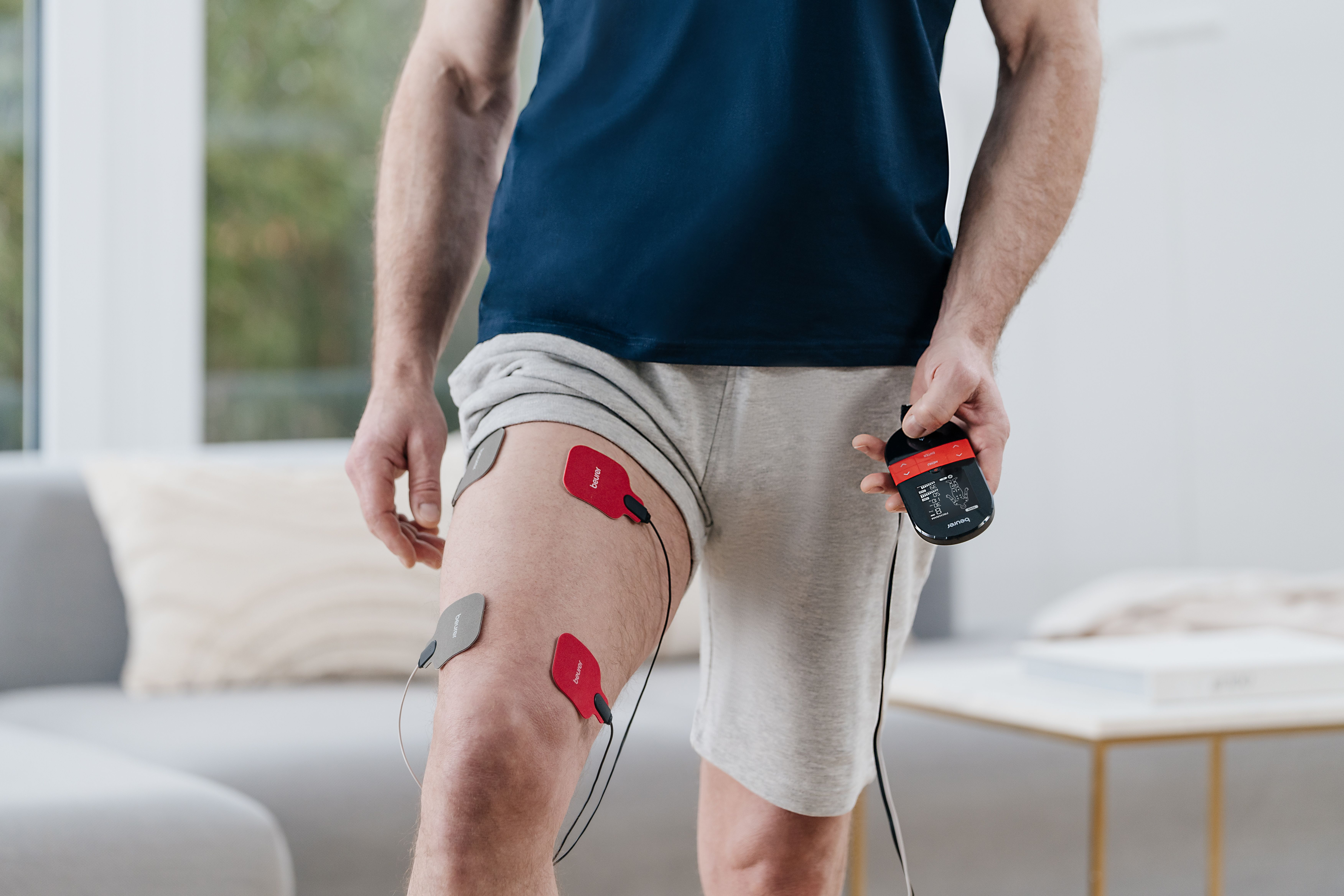 Mann mit Elektroden am Bein und einem Steuergerät in der Hand.