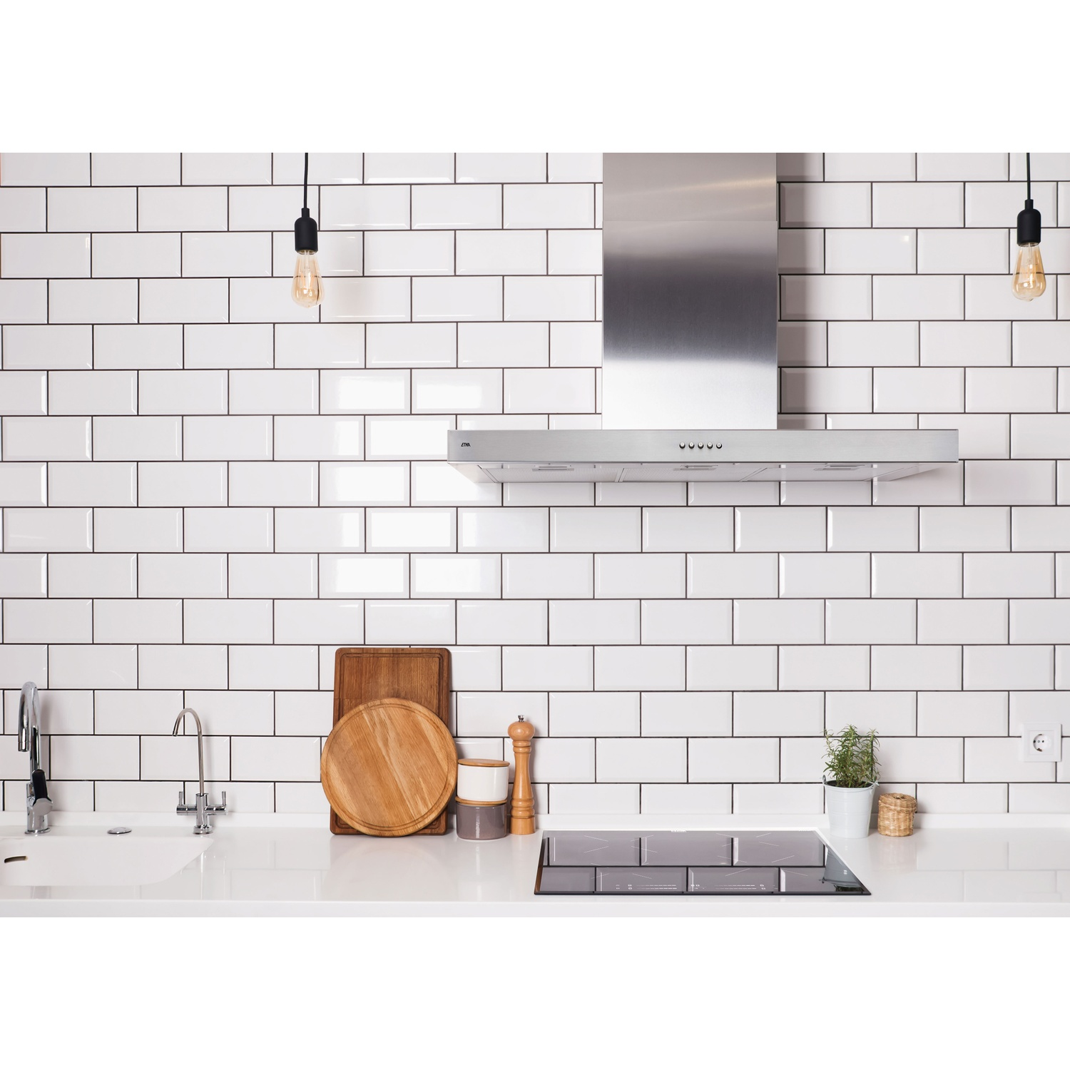Cuisine moderne avec carrelage métro blanc, hotte et plaque de cuisson inox.