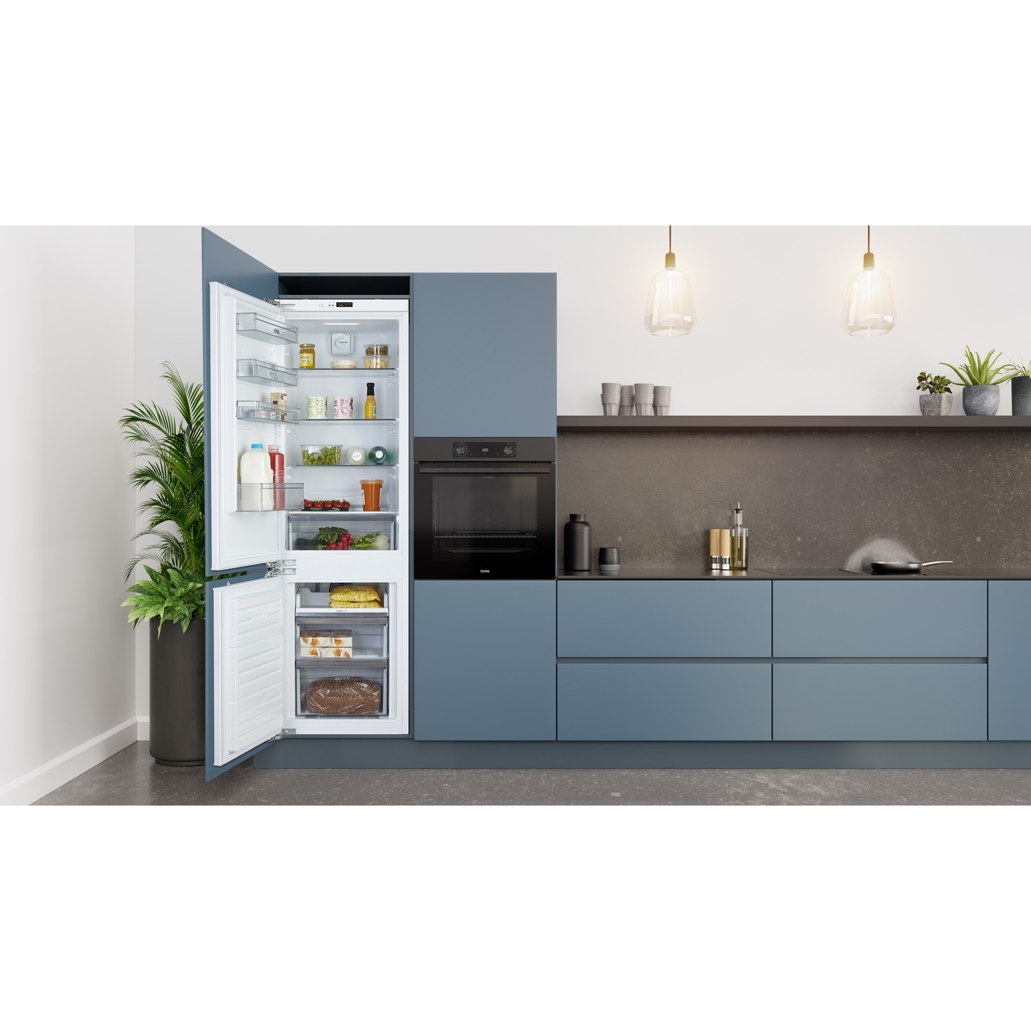 Open witte koelkast met eten, naast een zwarte oven en blauwe kasten.